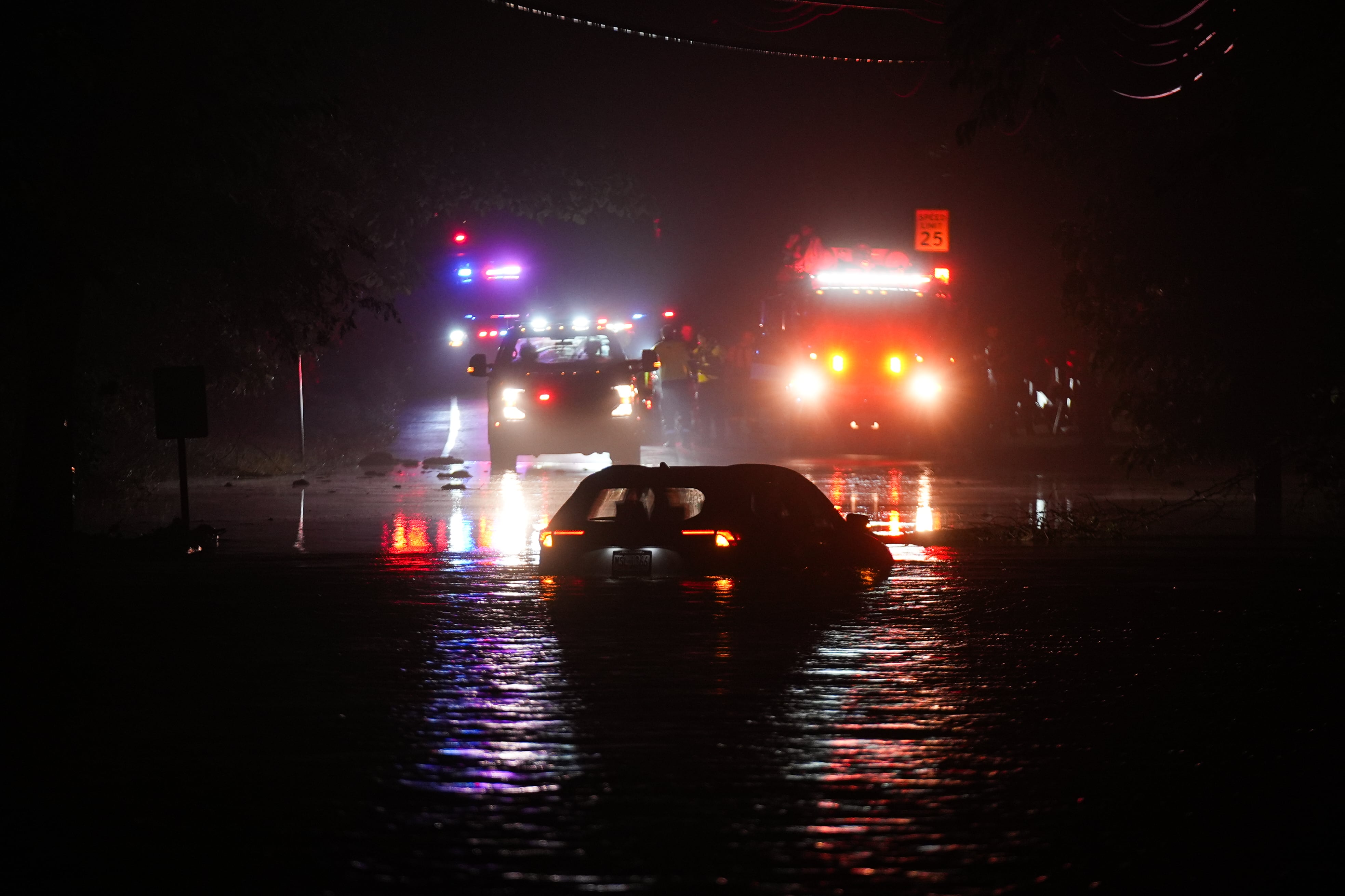Vehicle headlights shine on a flooded street.