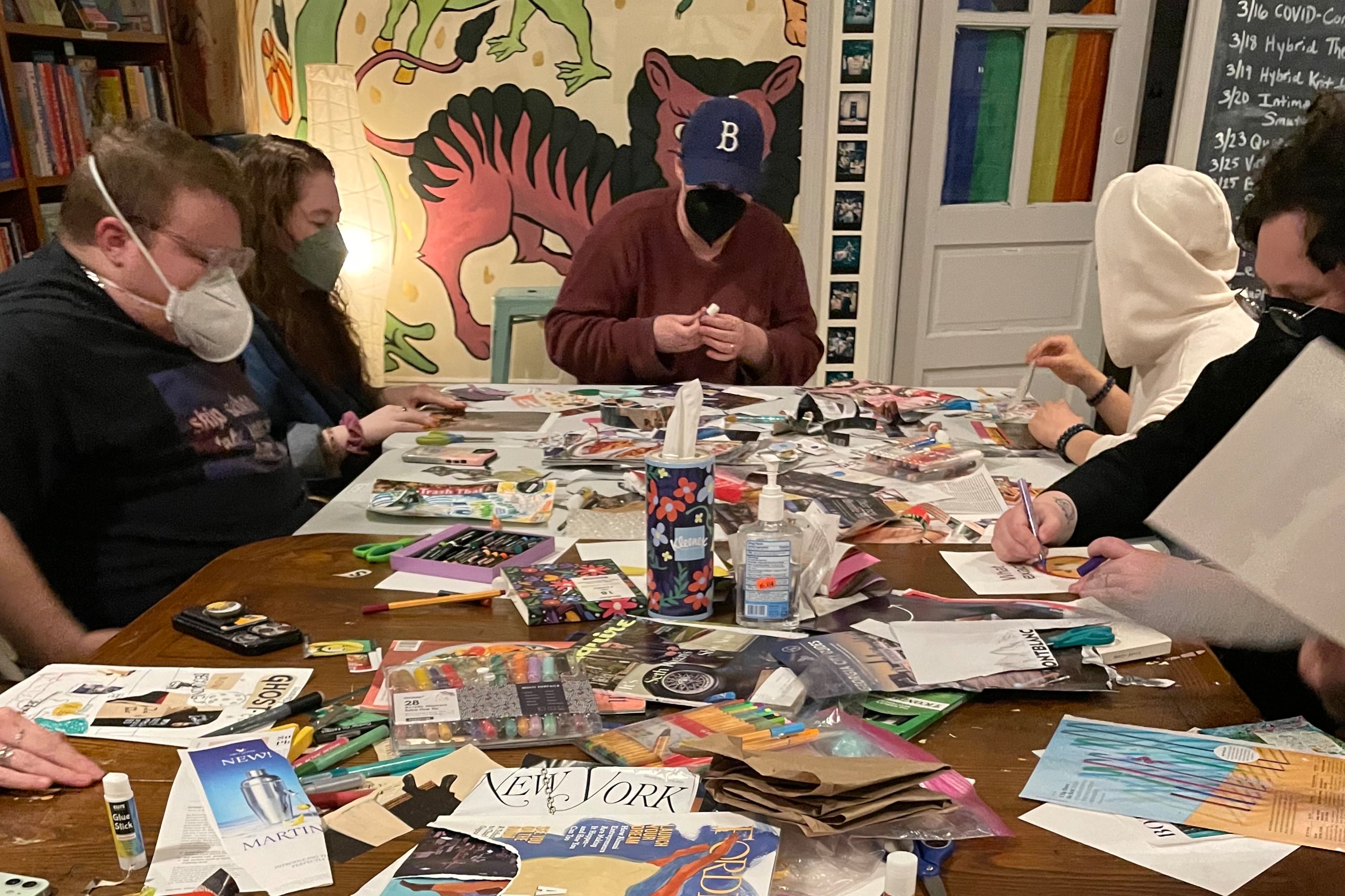 People wearing face masks do crafts around a table.