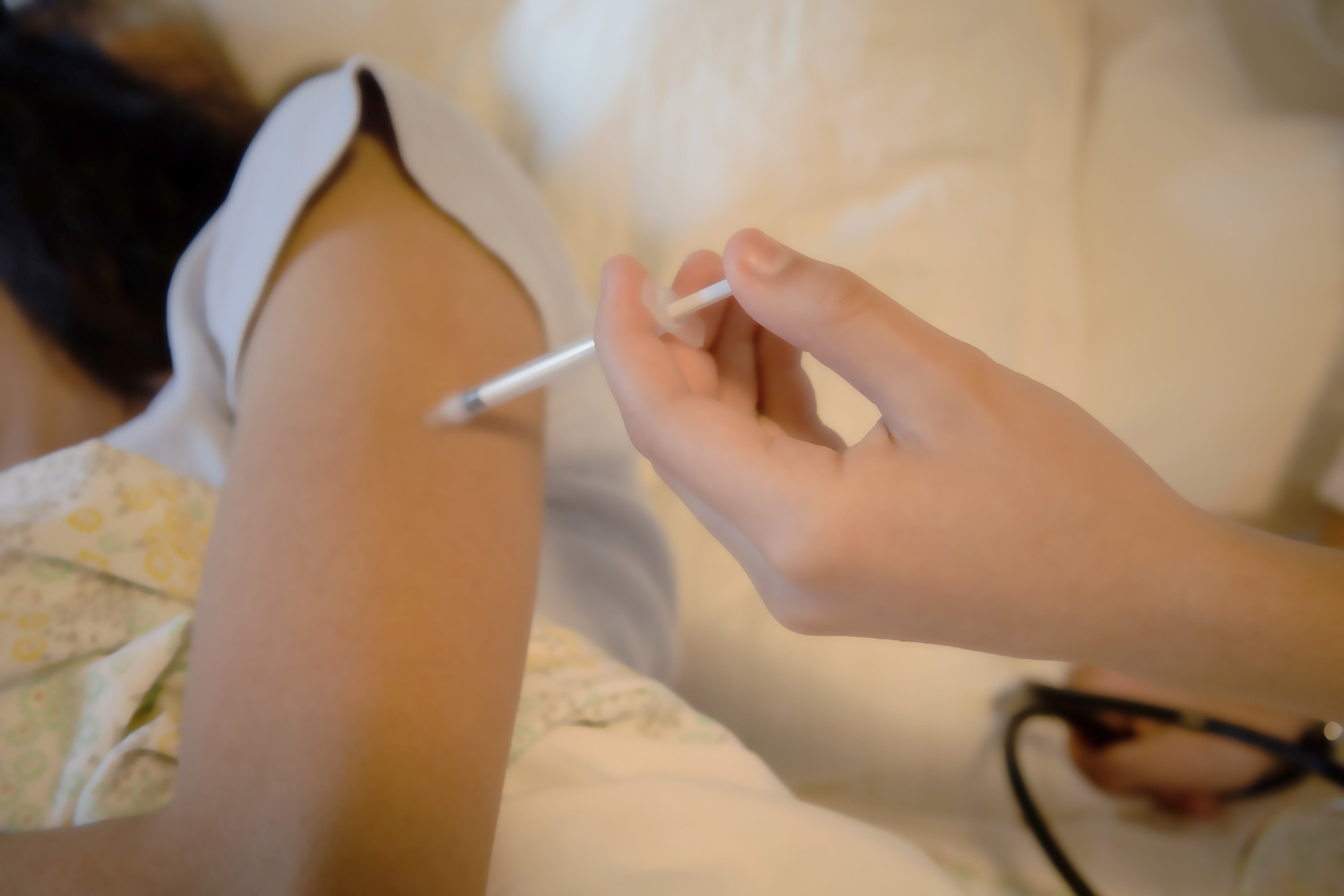 A girl's arm is injected with a vaccine shot.