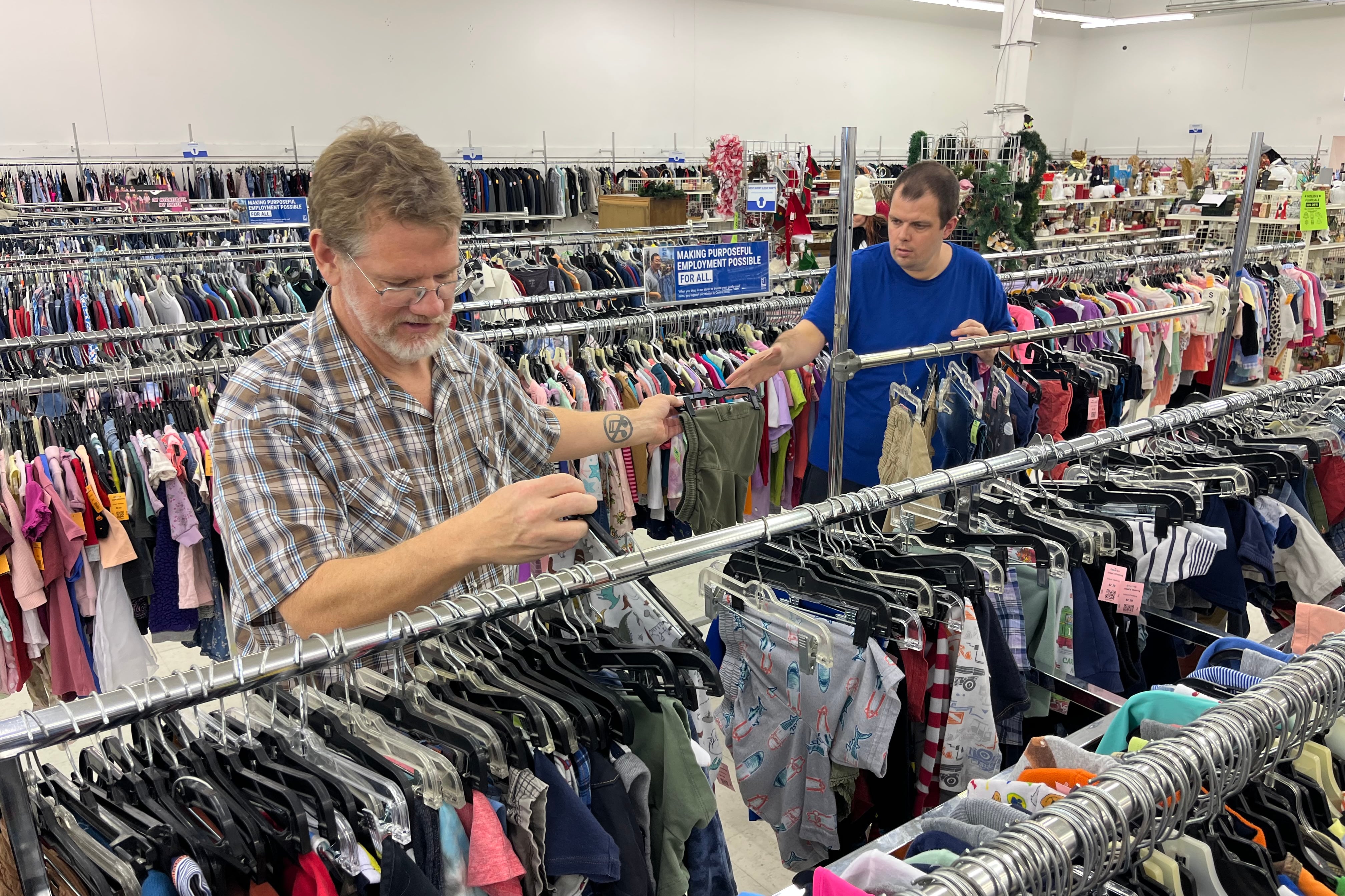 Two men sort clothing at a thrift store.