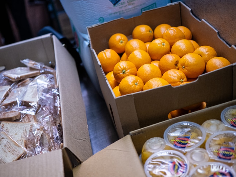 Oranges and fruit cups sit in boxes.