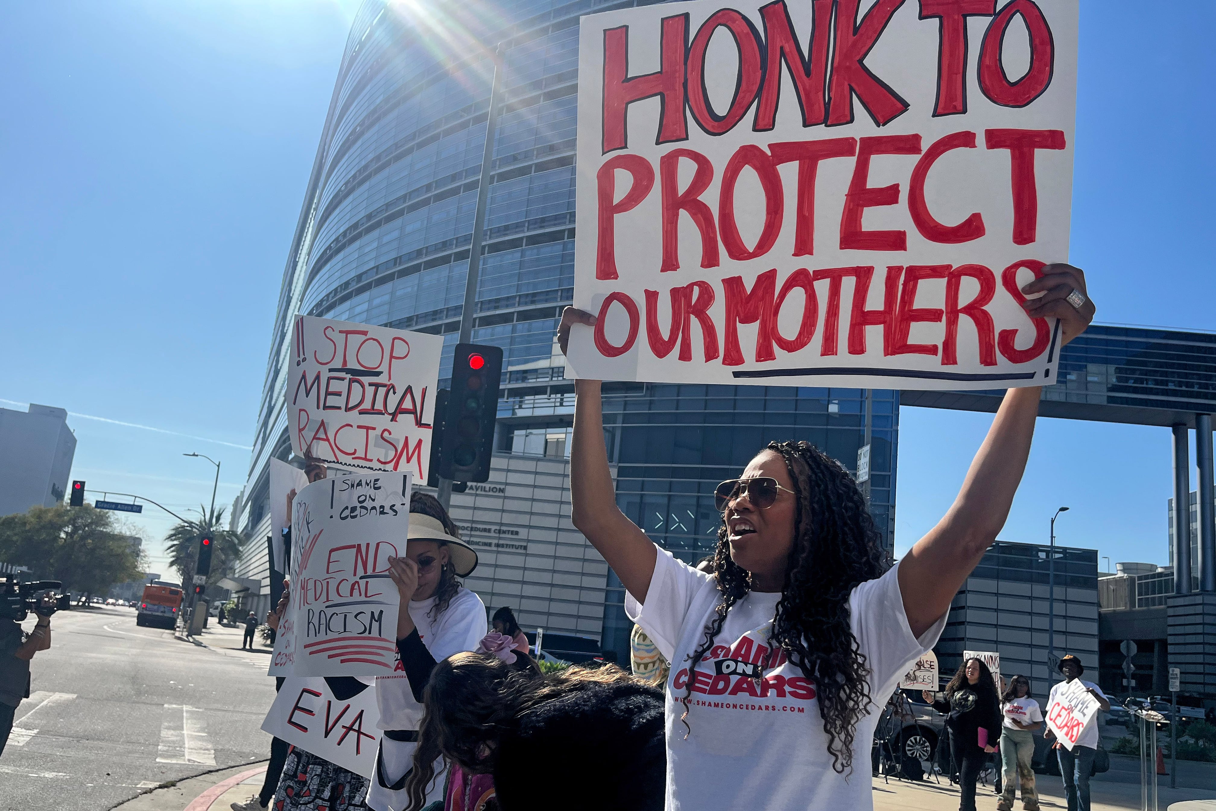 People hold signs during a protest outside a hospital.