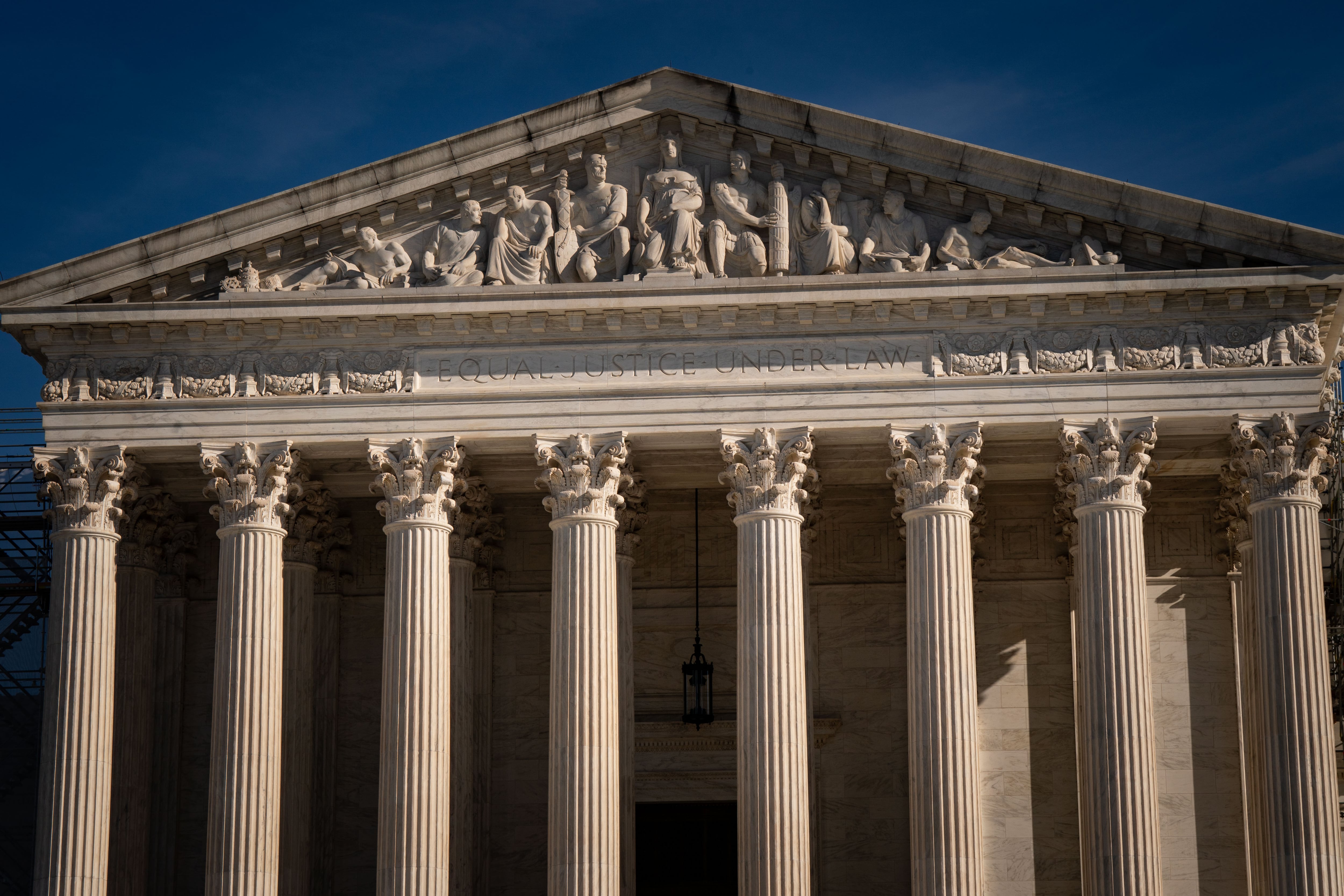 The top of the US Supreme Court building with a blue sky in the background.