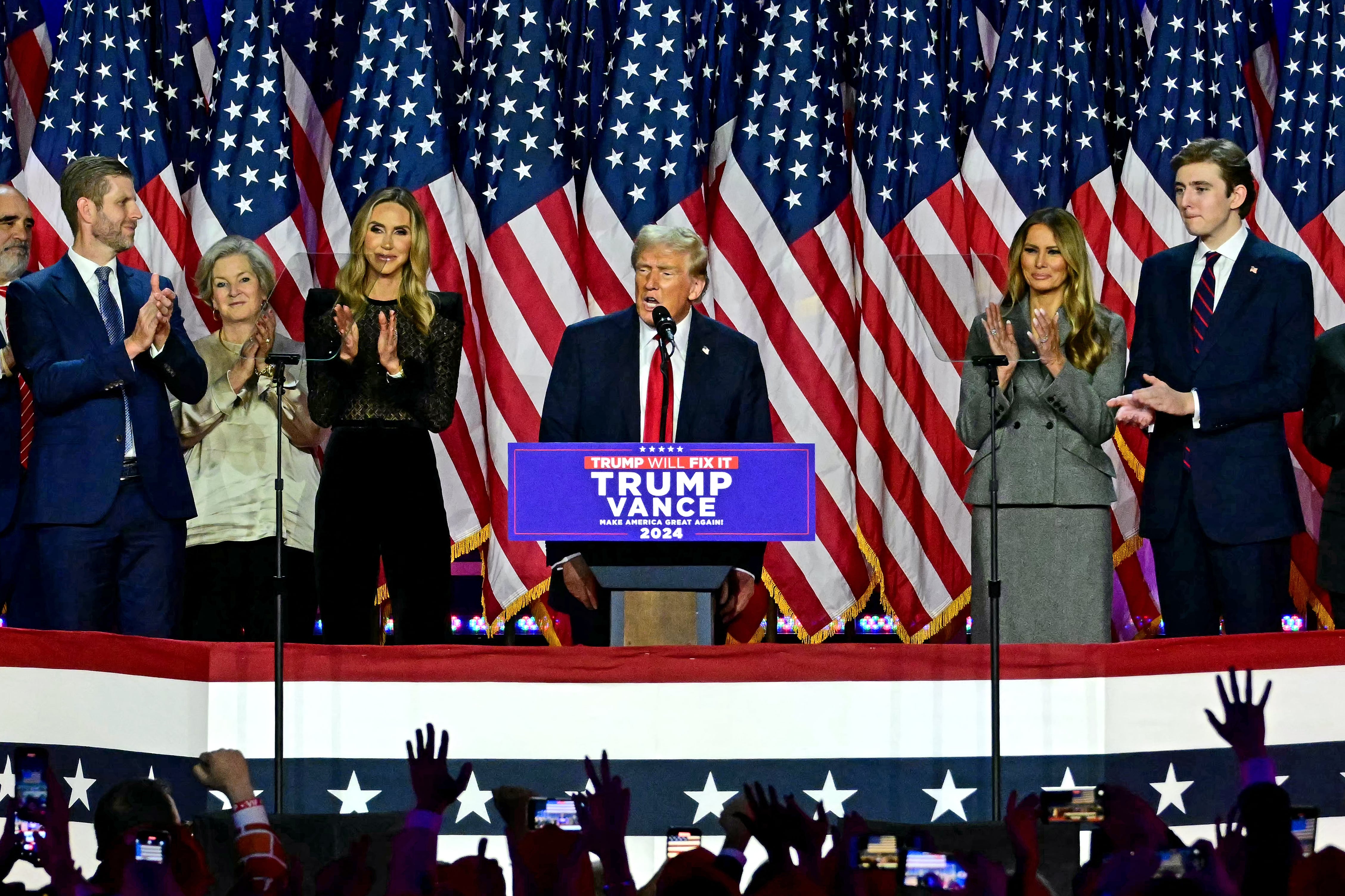 Donald Trump speaks from a podium, flanked by family members.