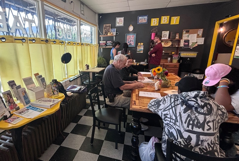 A bright cafe full of people sitting at a table.