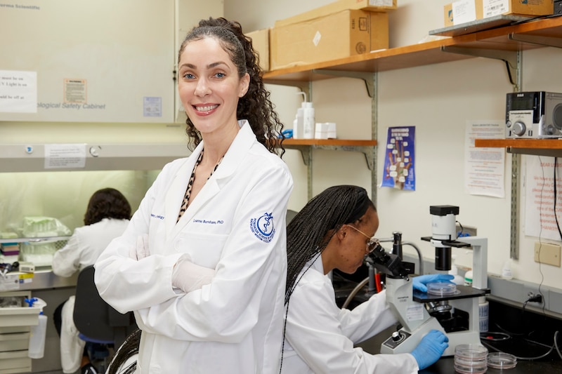 A doctor who researches cancer stands in a lab.
