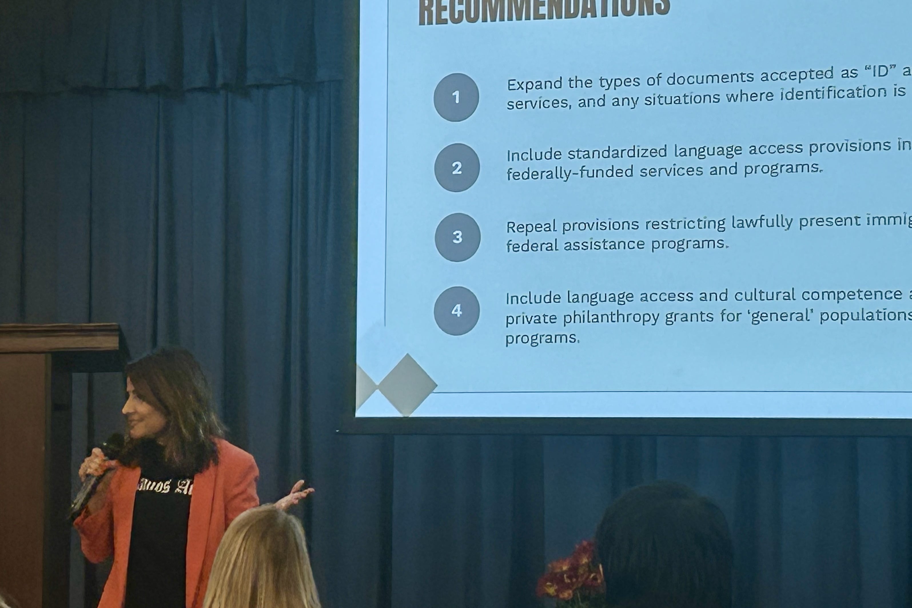 Gilda Pedraza stands in front of a large screen with text under a "Recommendations" heading.