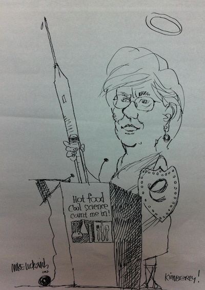 A black-and-white sketch shows Dr. Kimbi Hagen at a podium holding a giant syringe.