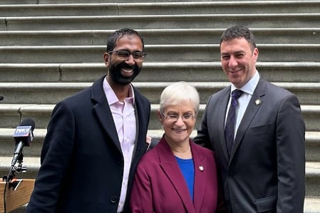 Shekar Krishnan, Lynn Schulman, and Eric Dinowitz pose for a photo outside a courthouse.