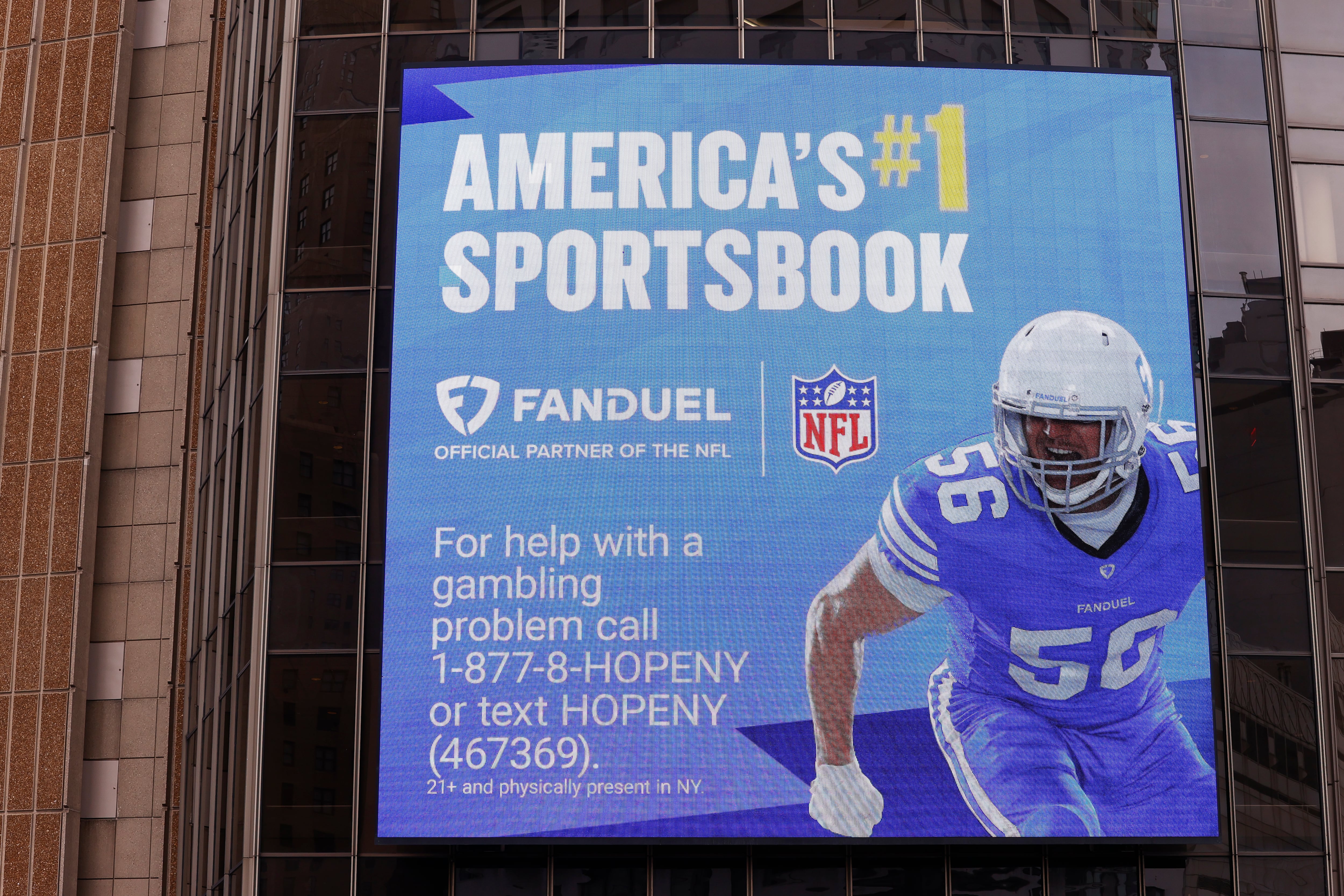 An ad for FanDuel on the side of a building also contains the phone number for New York's gambling crisis line.