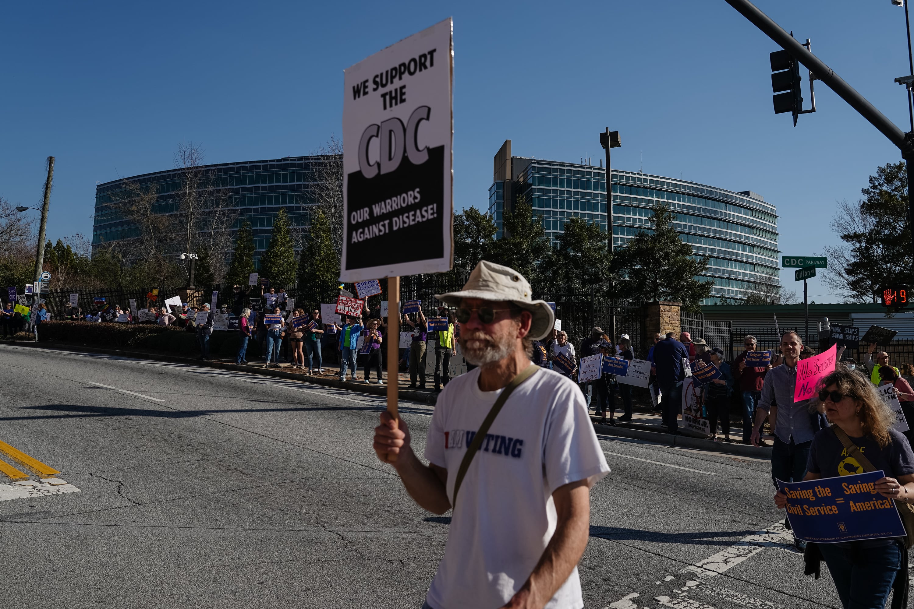 People hold signs outside the Centers for Disease Control and Prevention to protest funding cuts.
