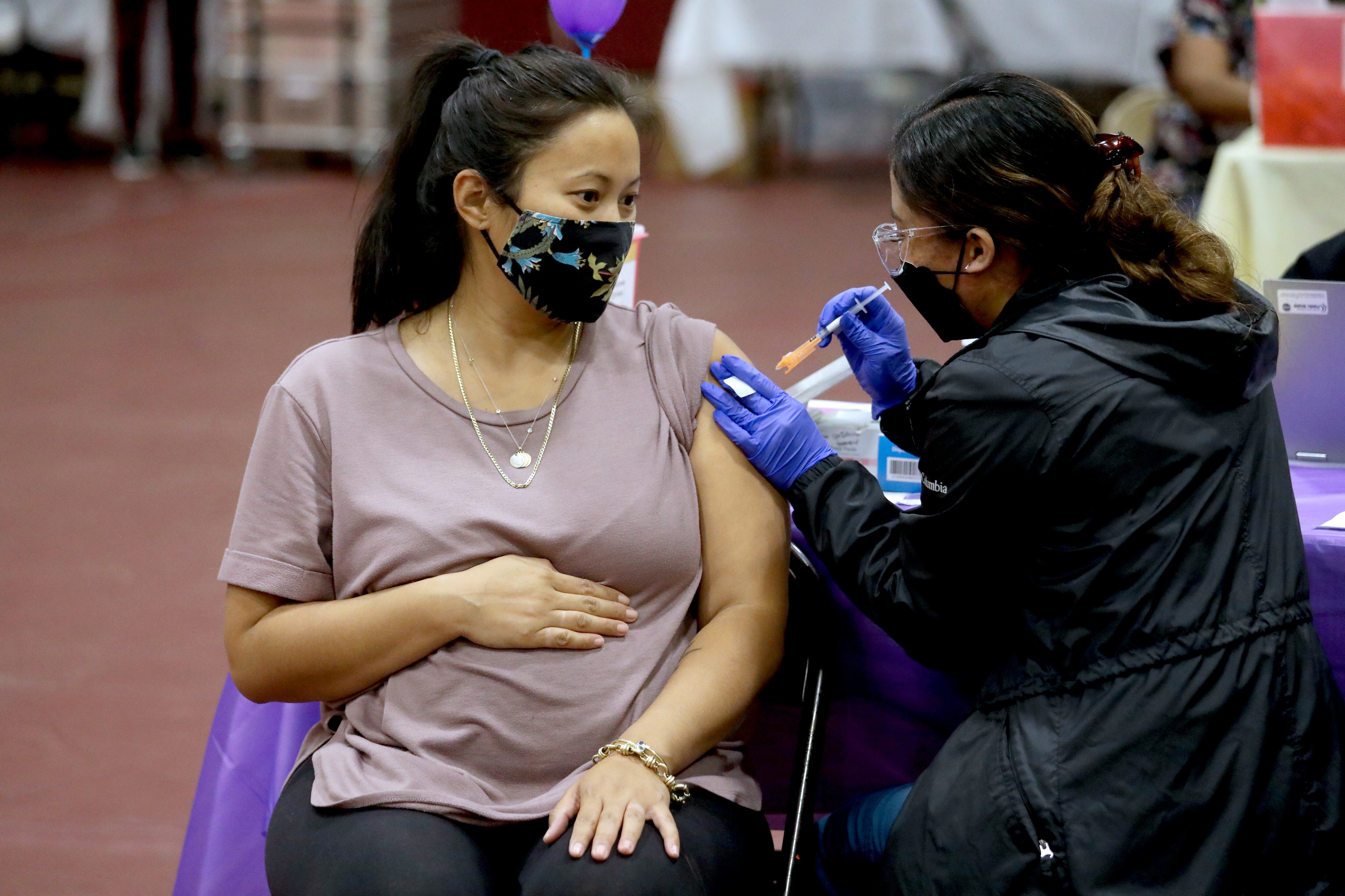 A pregnant woman gets a Covid vaccine shot in her arm.