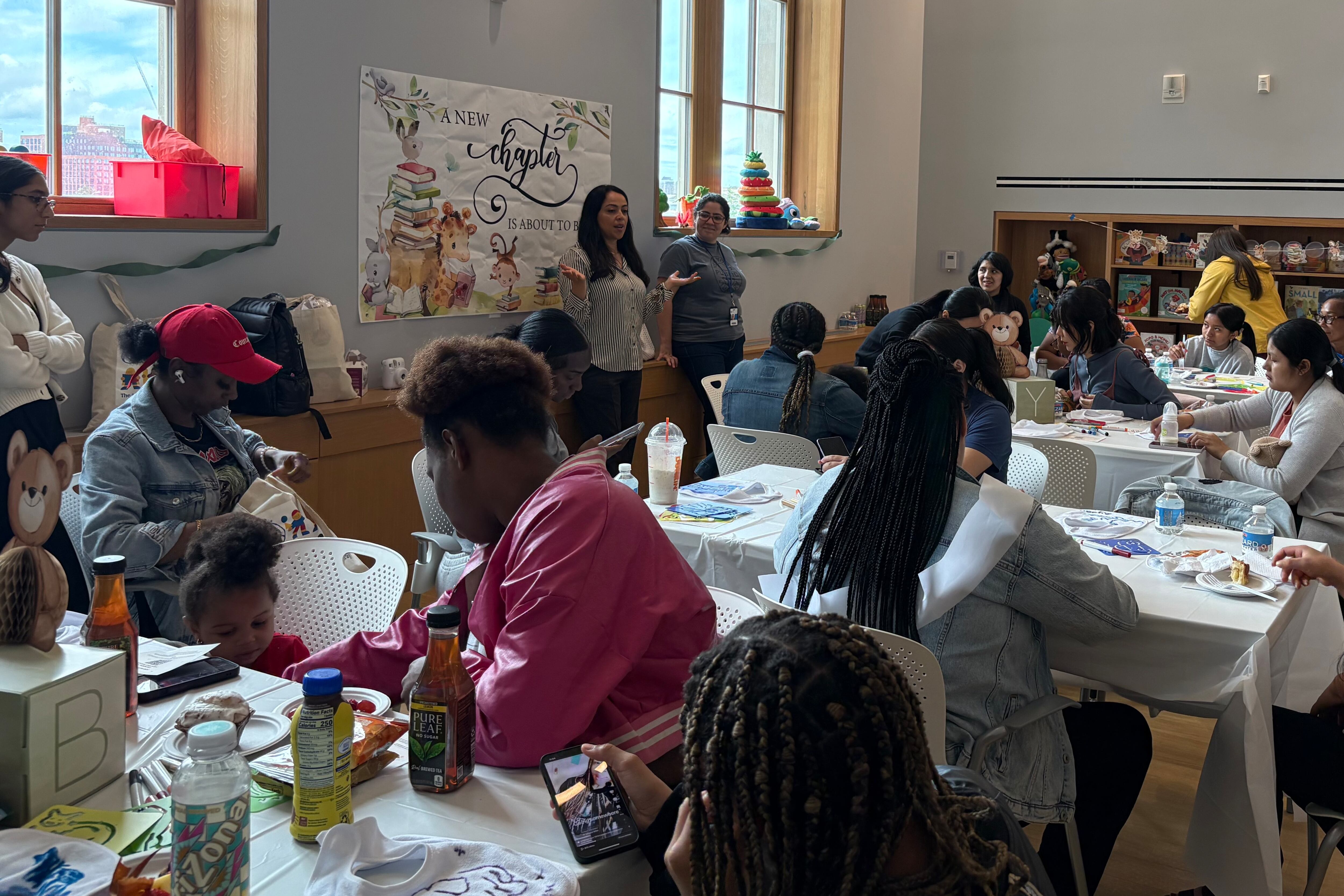 A group of women sit around tables at an event to distribute health kits for pregancy.