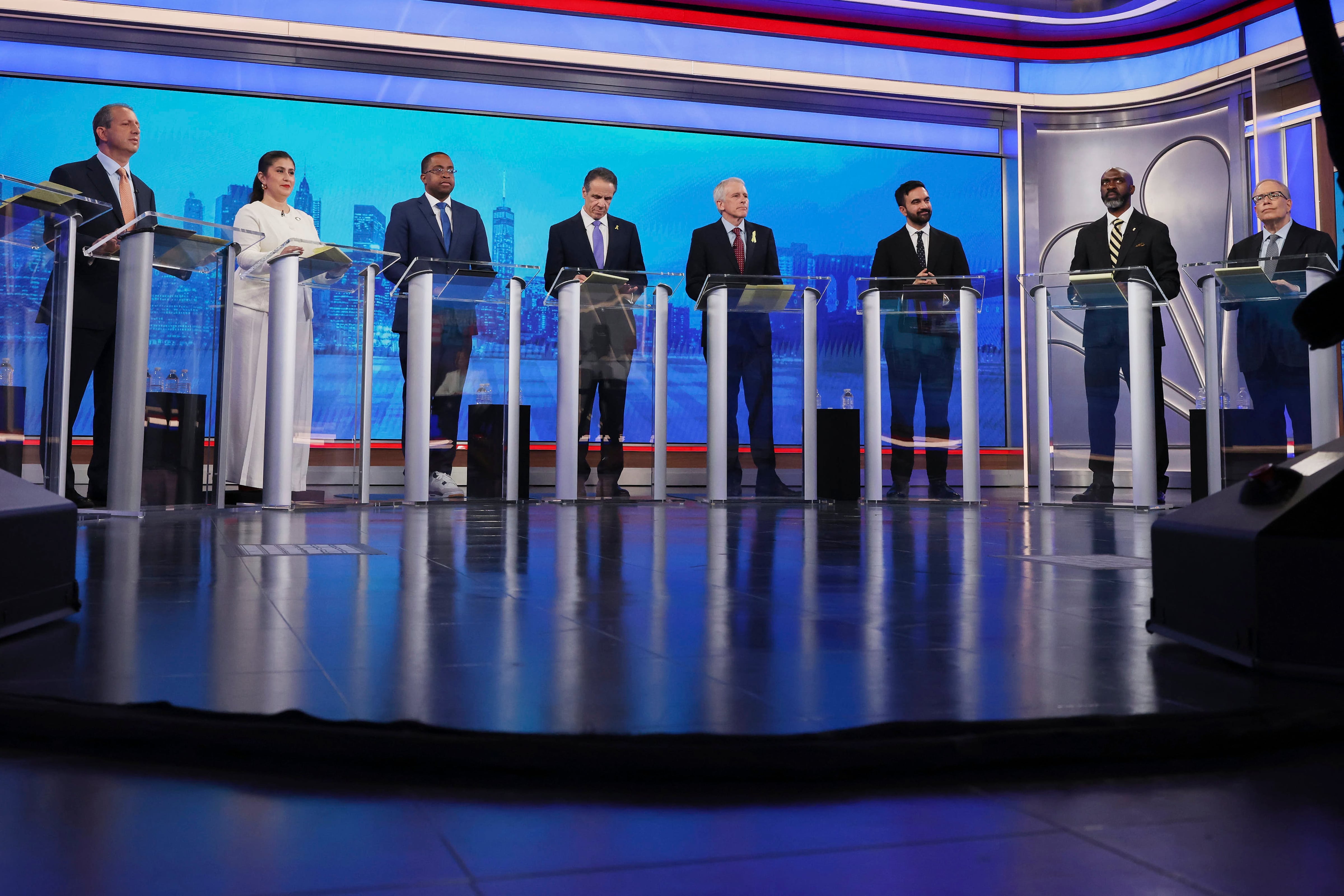 Nine candidates in the New York City mayoral primary election stand at podiums during a debate.