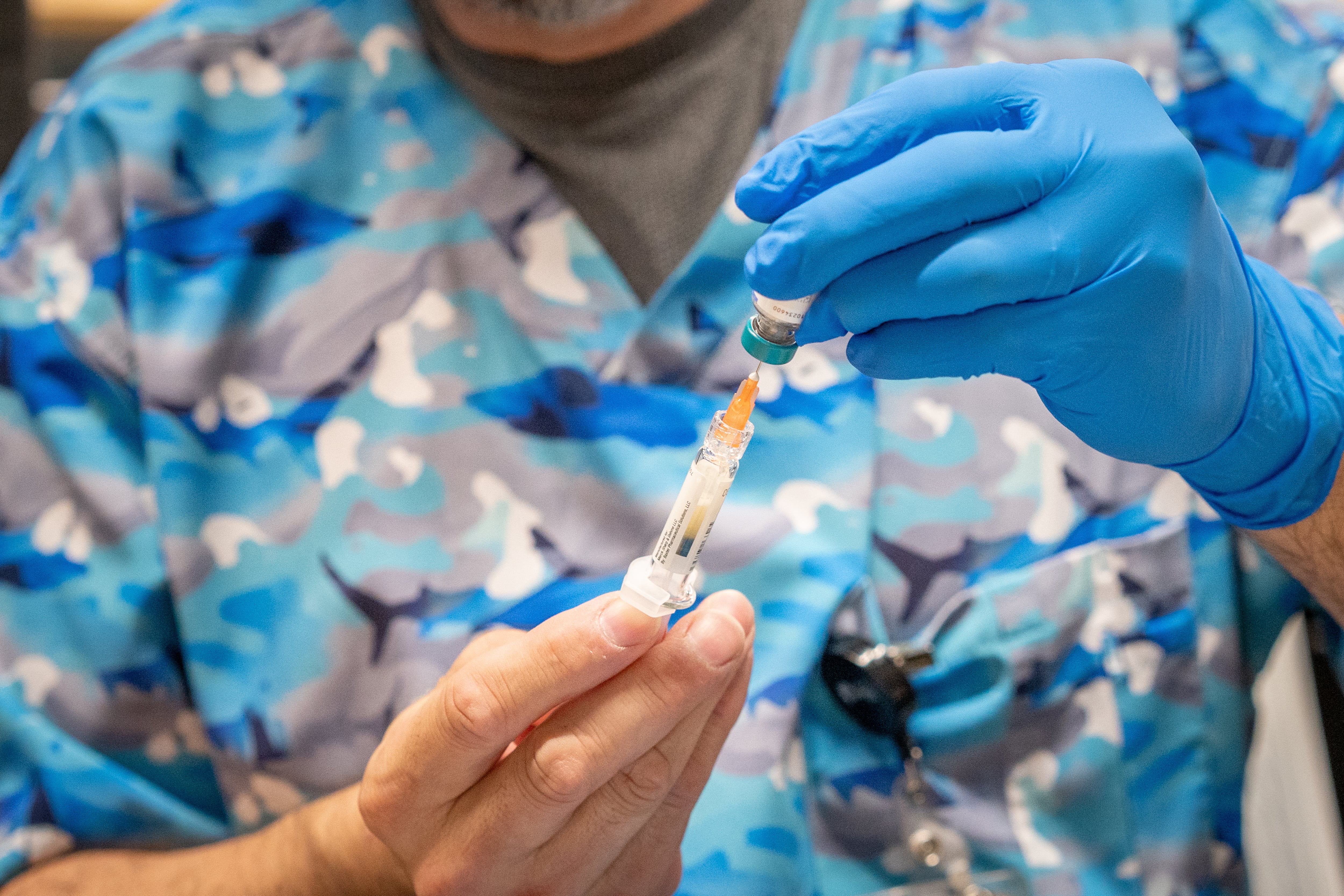 A healthcare worker holds a syringe for a vaccine.