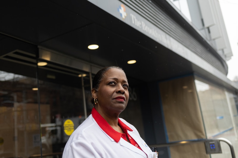 A nurse stands on a city street.