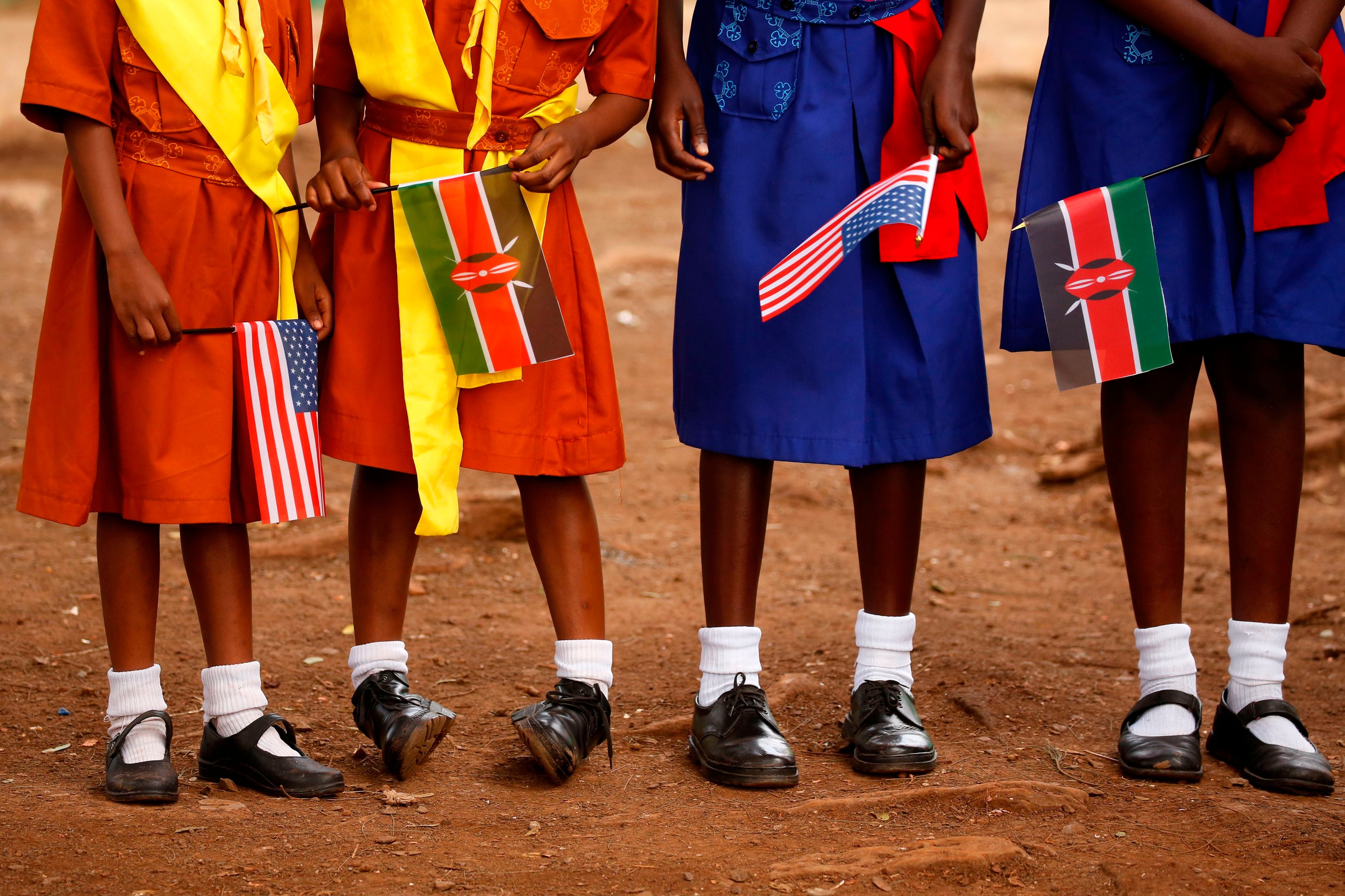 Four girls in colorful dresses hold flags.