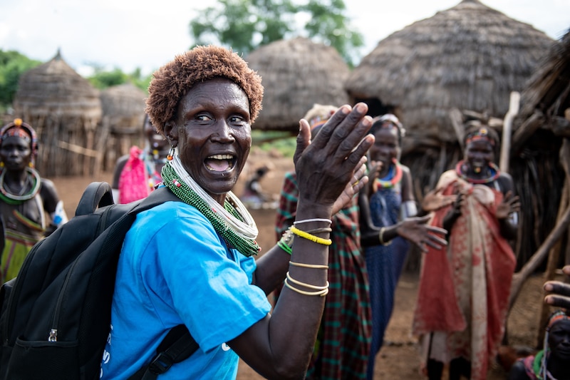A woman claps her raised hands in a South Sudanese village.