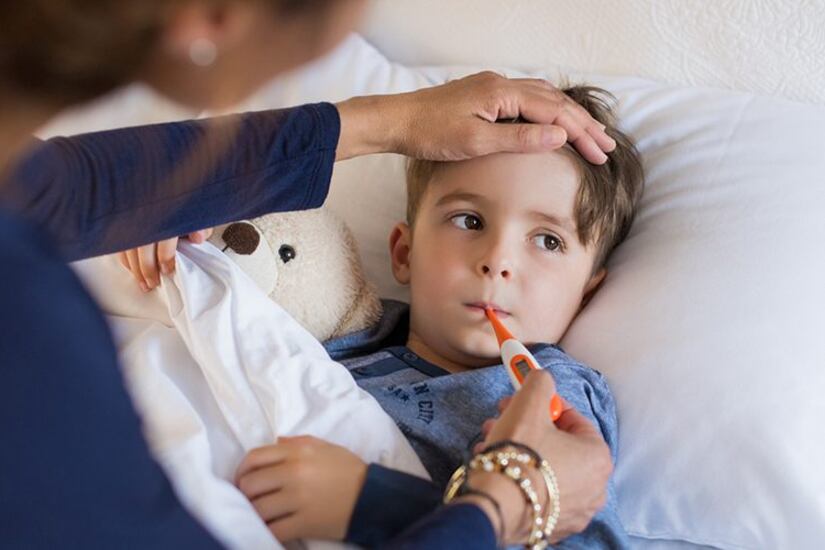 An adult takes the temperature of a sick child.