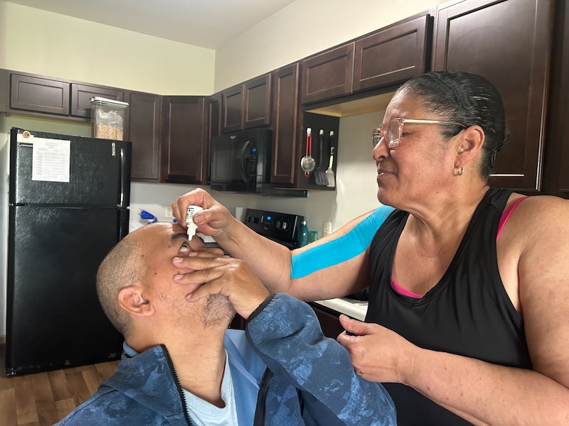 Wanda Serrano squeezes medicated drops into her husband's eyes.