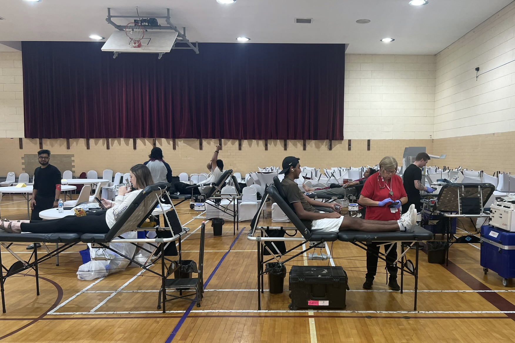 People sit in chairs or stand in a gymnasium.