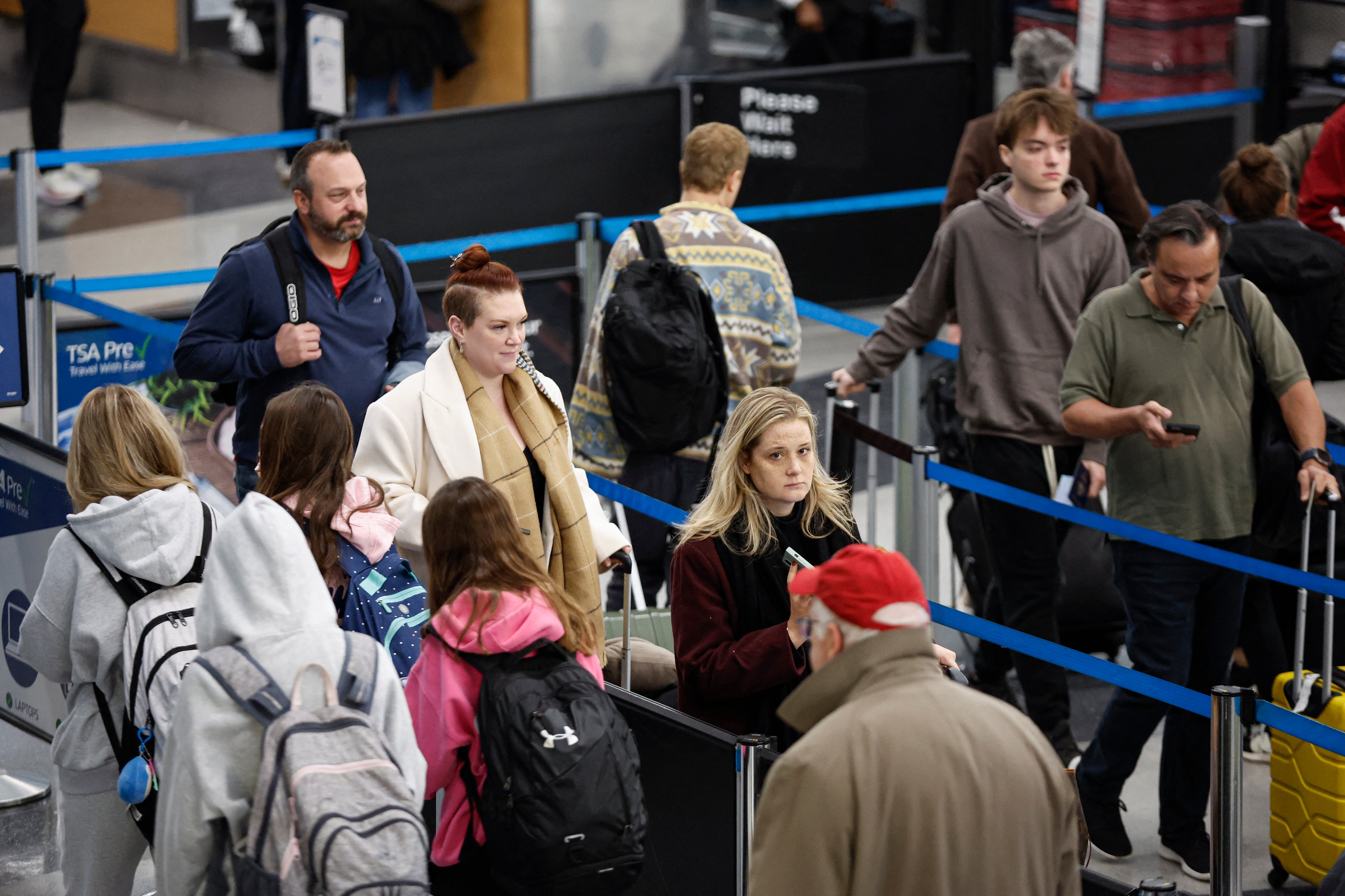 Travelers wait in line at an airport security checkpoint.