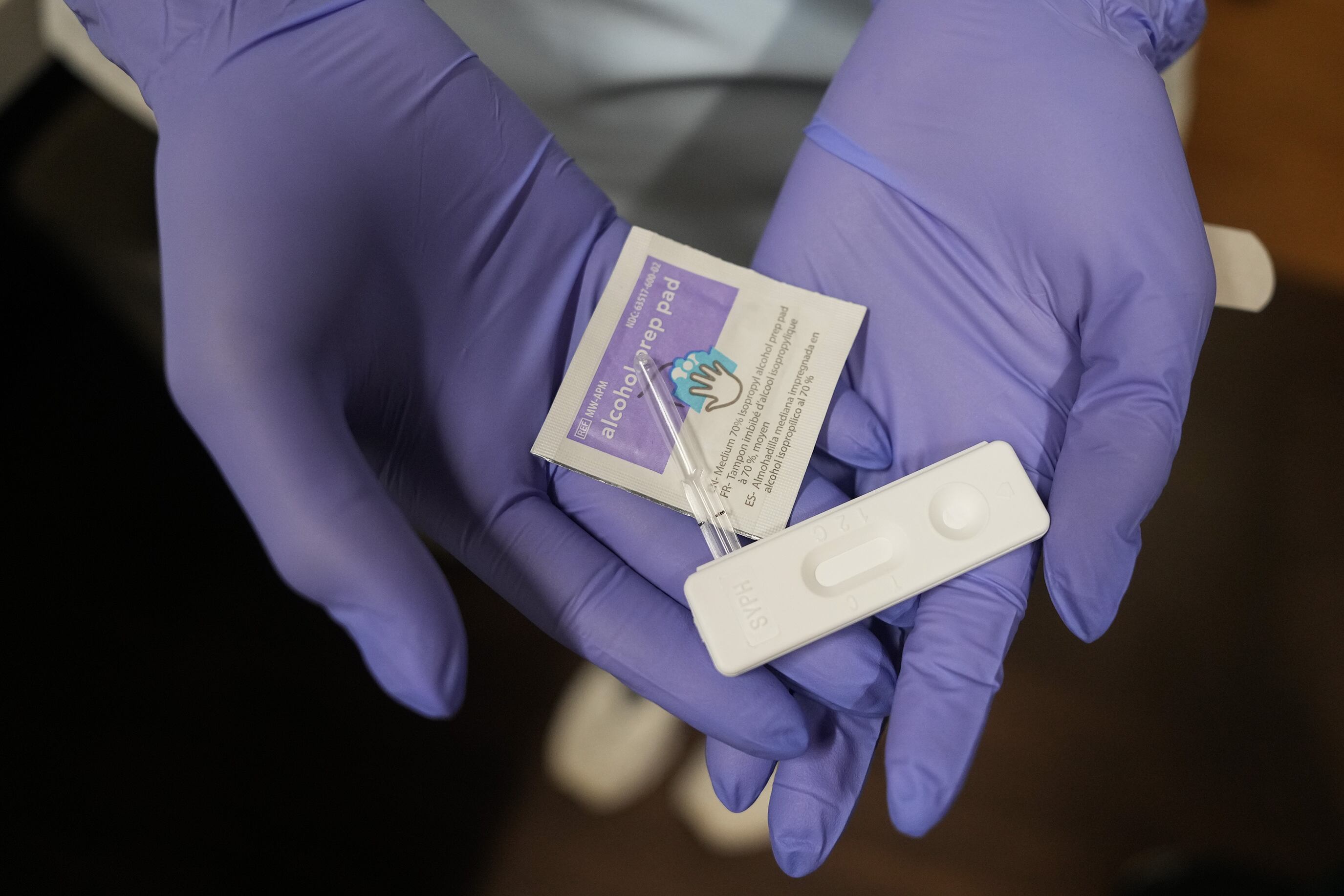 Two gloved hands hold a rapid test for congenital syphilis.