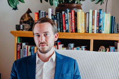A portrait of William Herkewitz in front of a bookshelf.