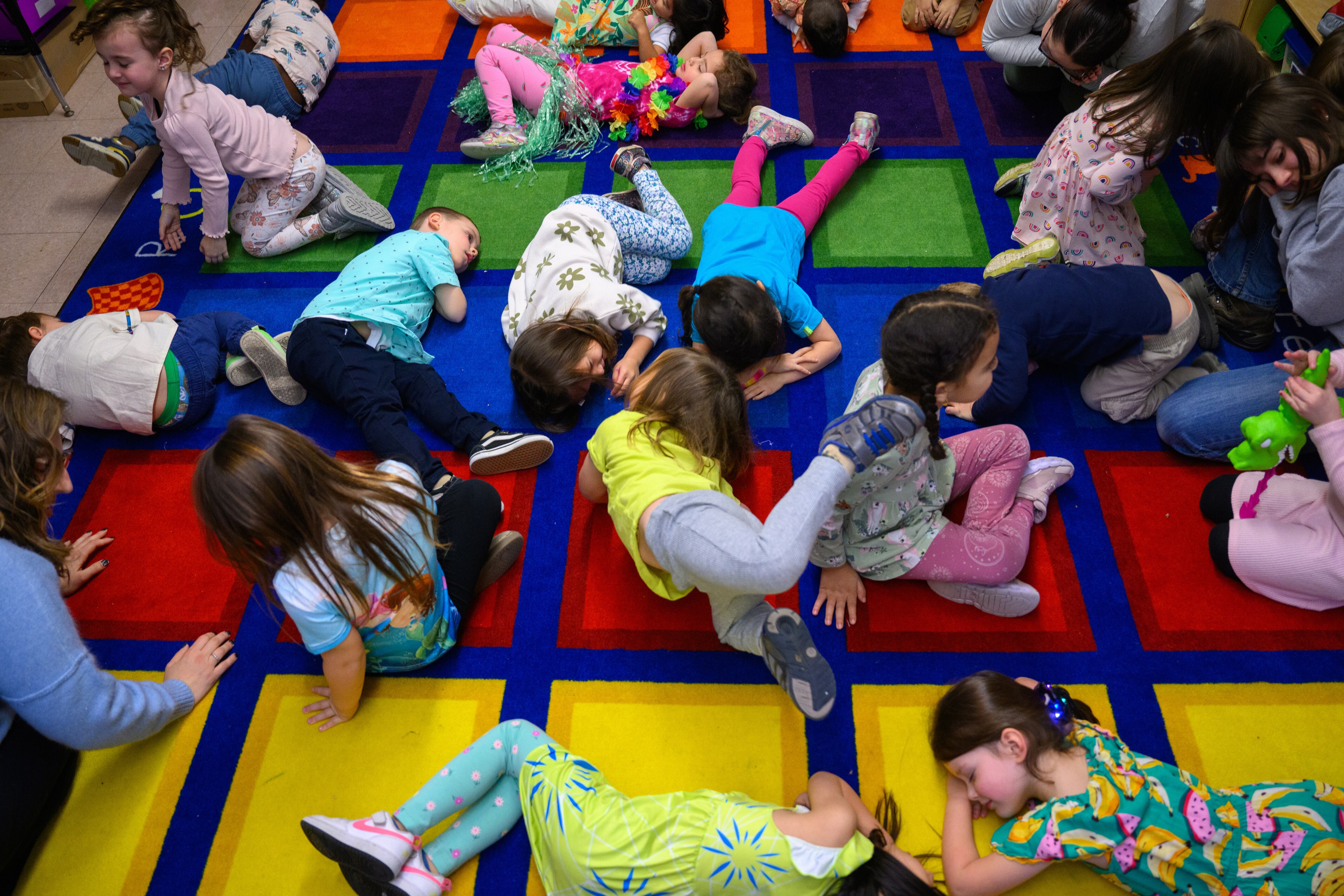 An aerial photograph of a group of young students who are resting on a colorful carpet.