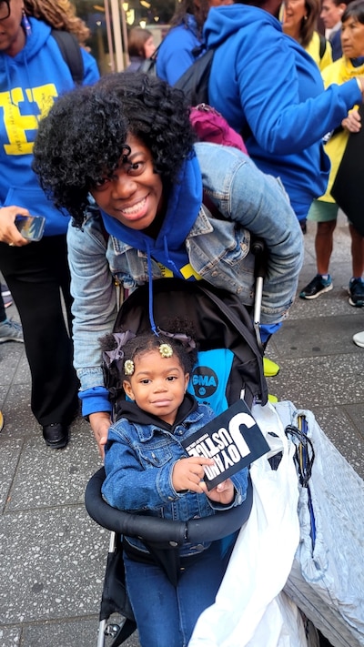 Keturah Queen smiles from a behind a stroller holding her young daughter.