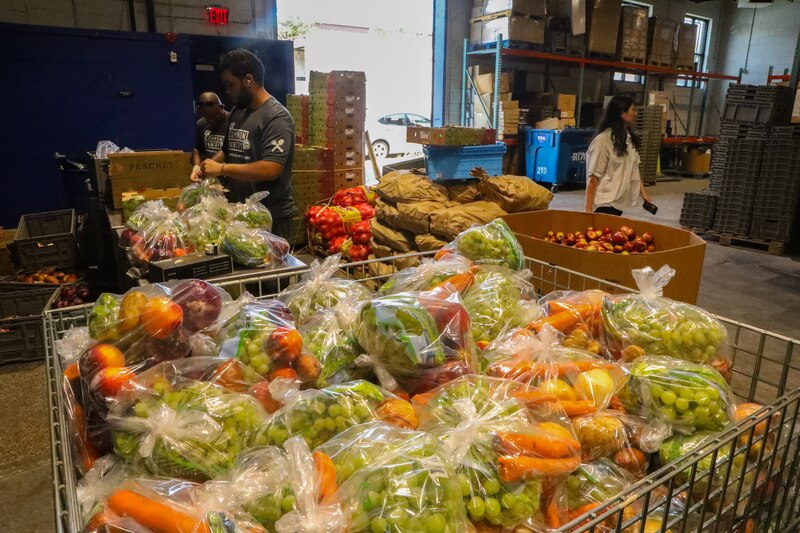 Workers pack produce in a warehouse.