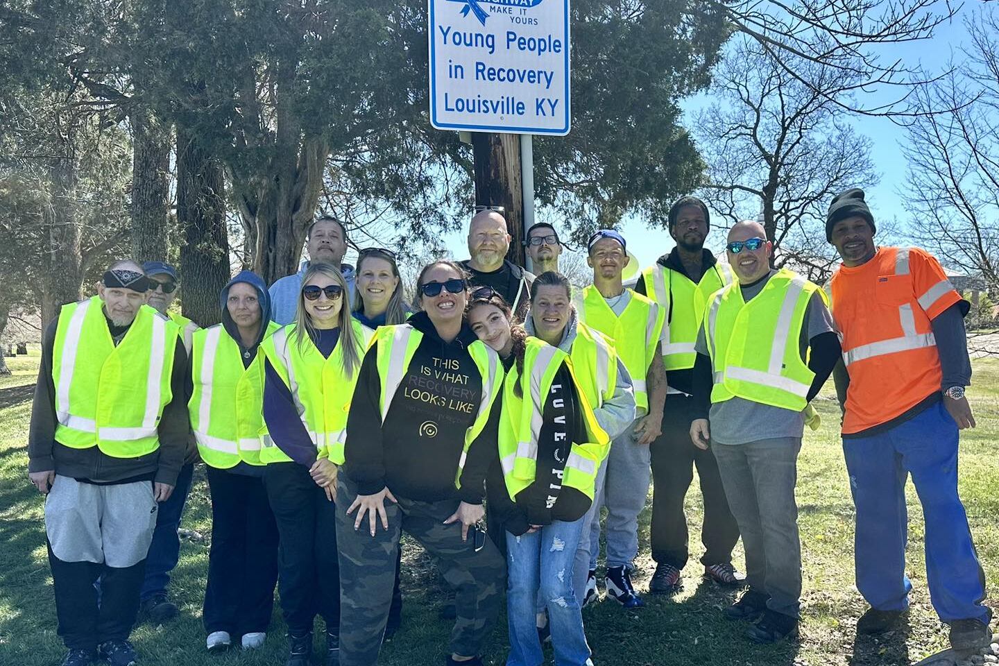 A group of young people wearing neon vests poses for a photo.