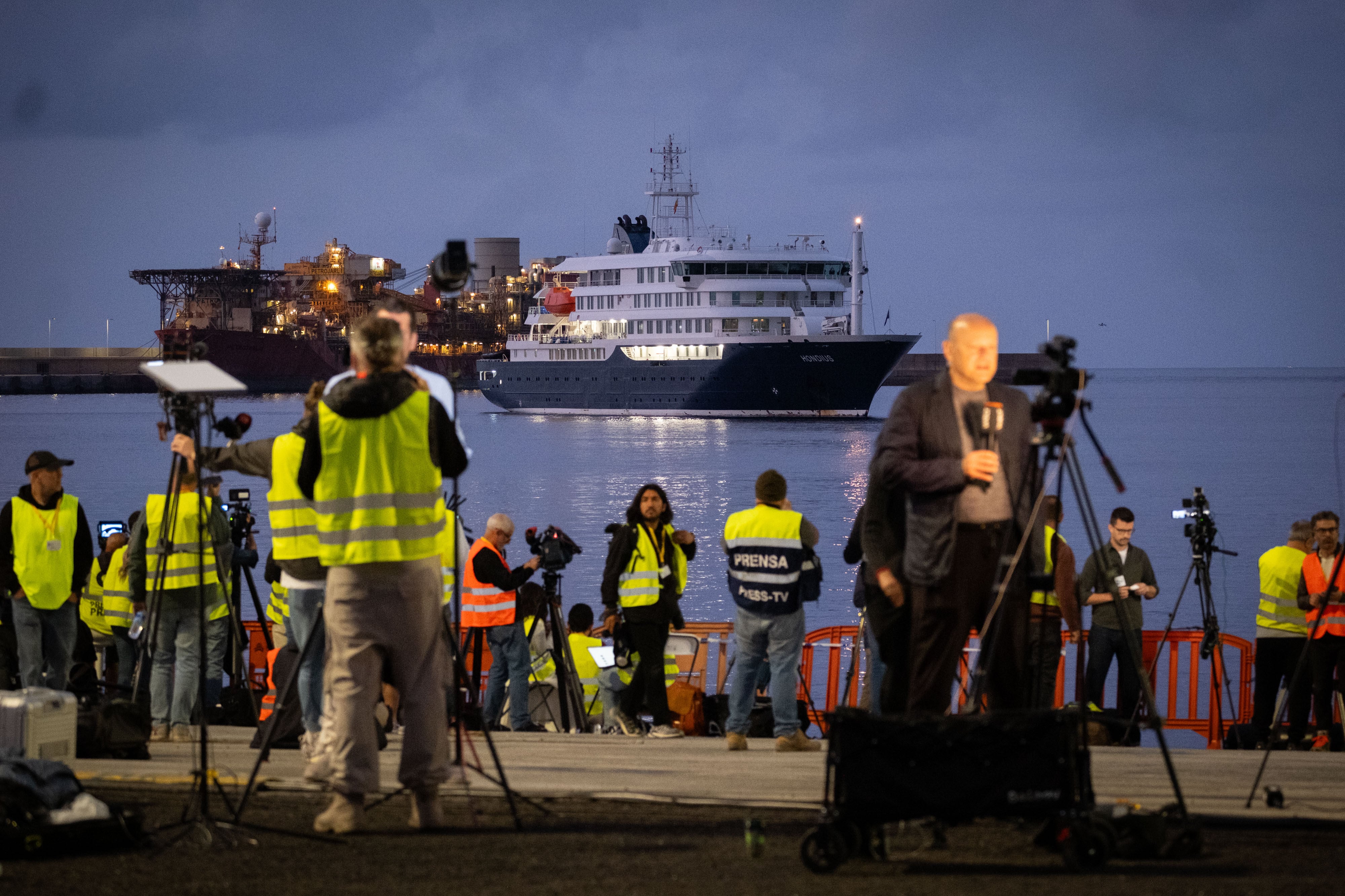 Reporters wait for a cruise ship to dock.