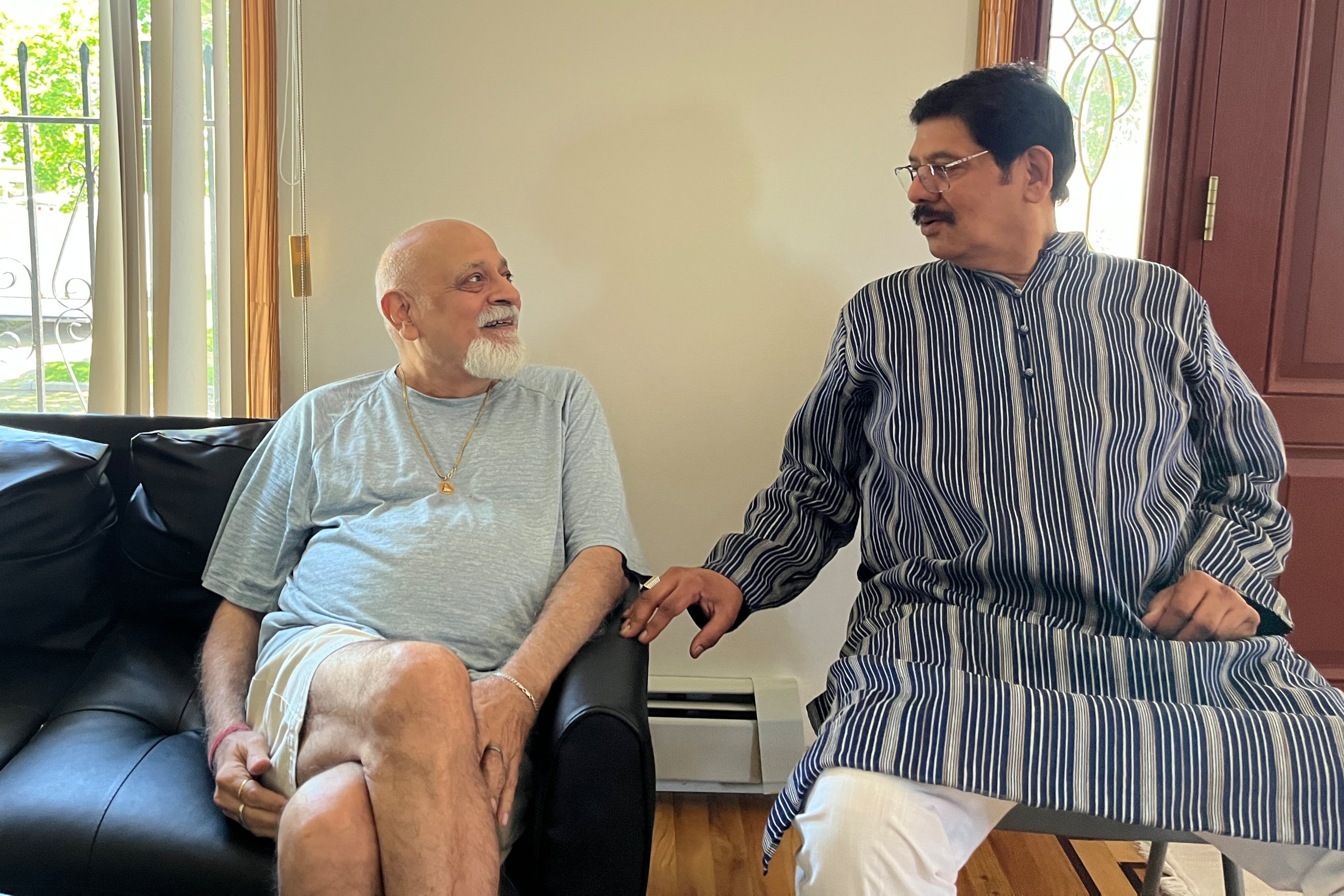 Two men sit for a chat in an apartment.