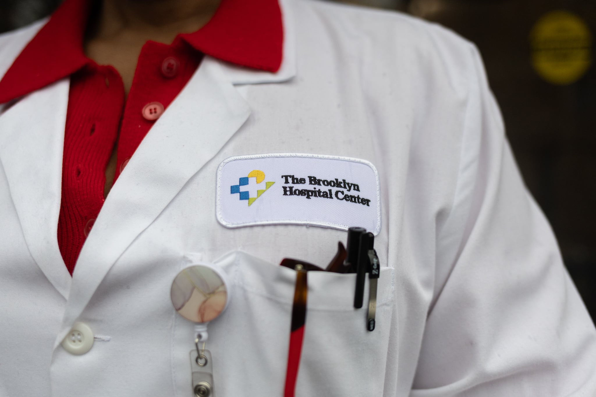 A closeup of a nurse in her white coat labeled Brooklyn Hospital Center.