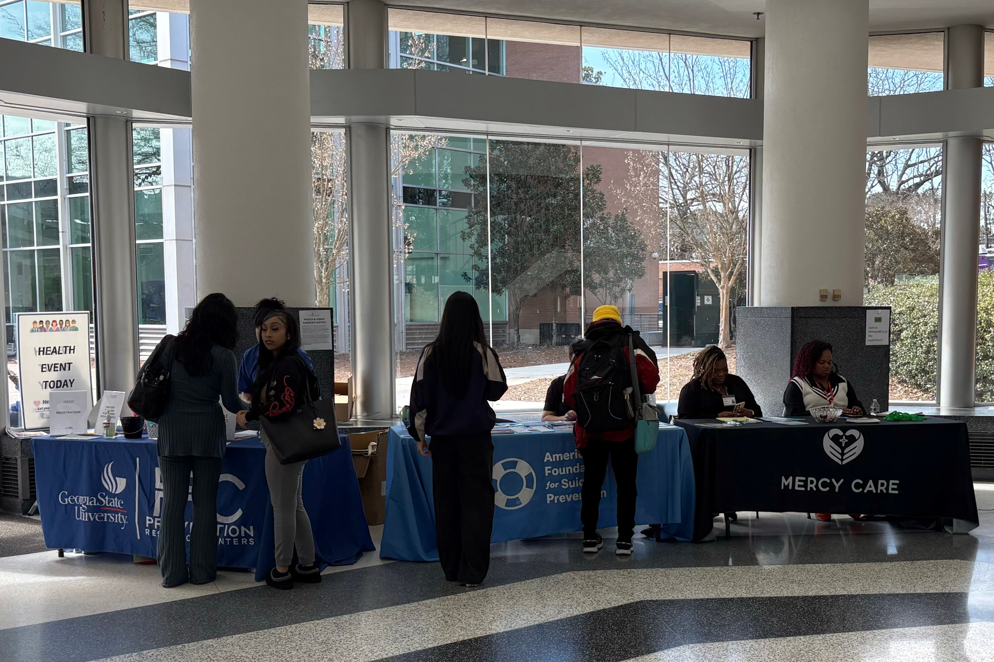A group of people stand around tables in a building.