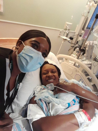 Eboni Tomasek lies in a hospital bed as her doula, Keosha McLamb, stands by.