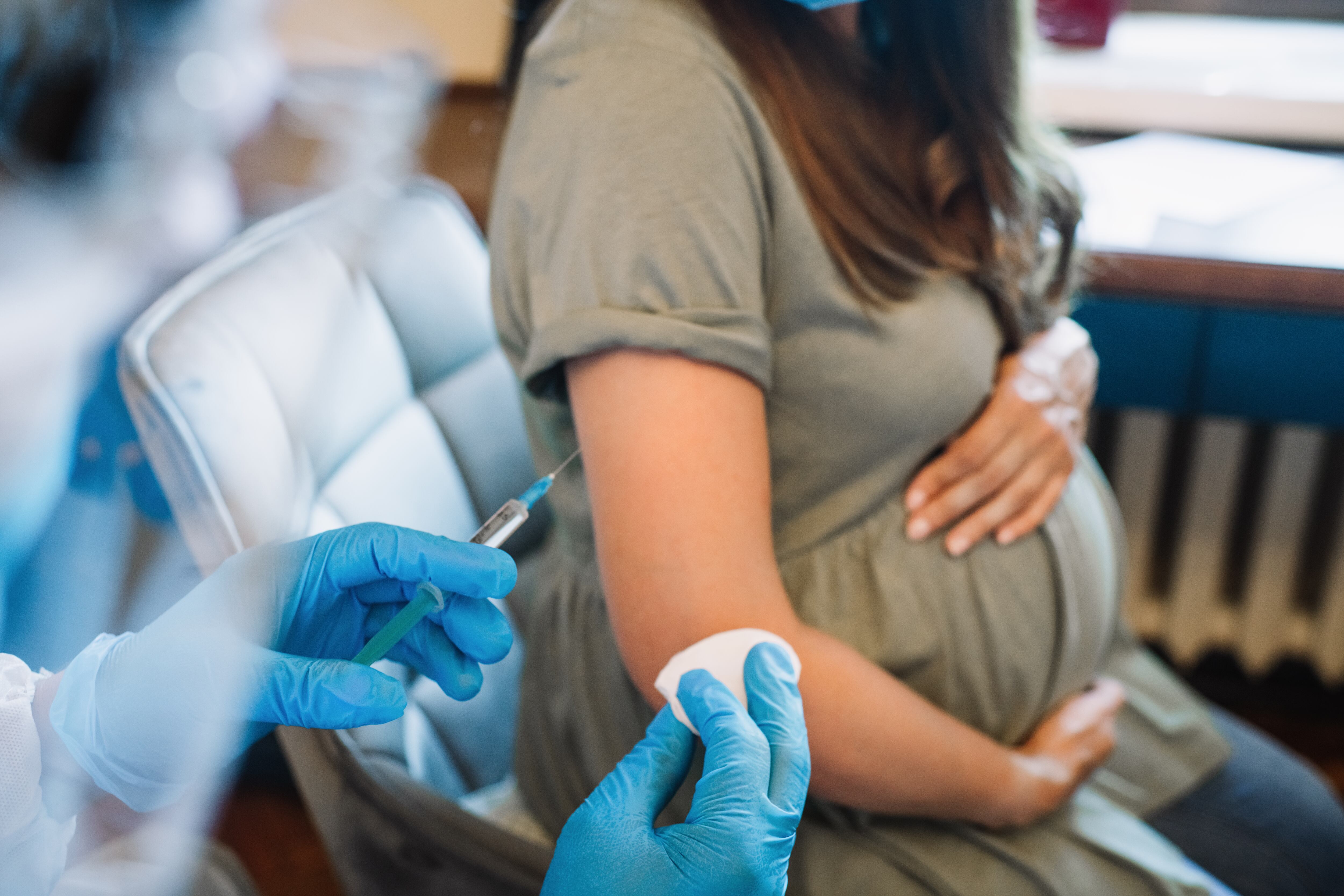 A pregnant woman gets a shot in the arm.