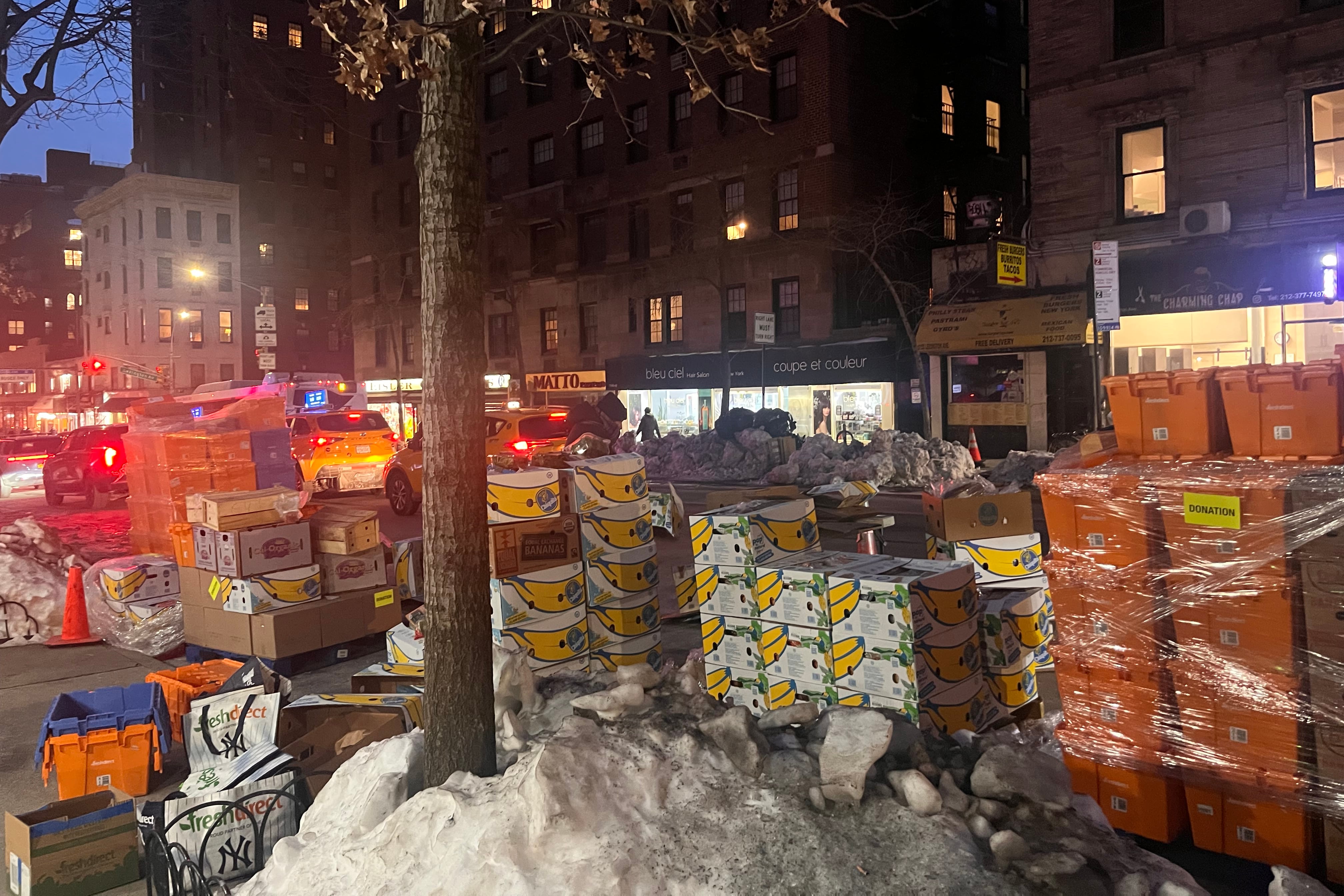 Boxes of food are stacked on a city street.