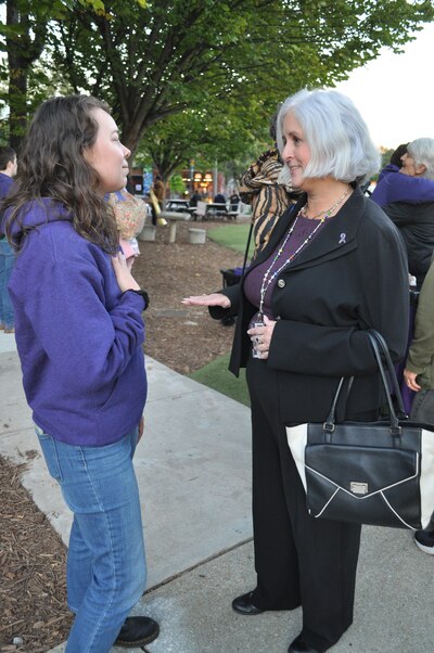 Two women stand talking at an event to honor victims of domestic violence.