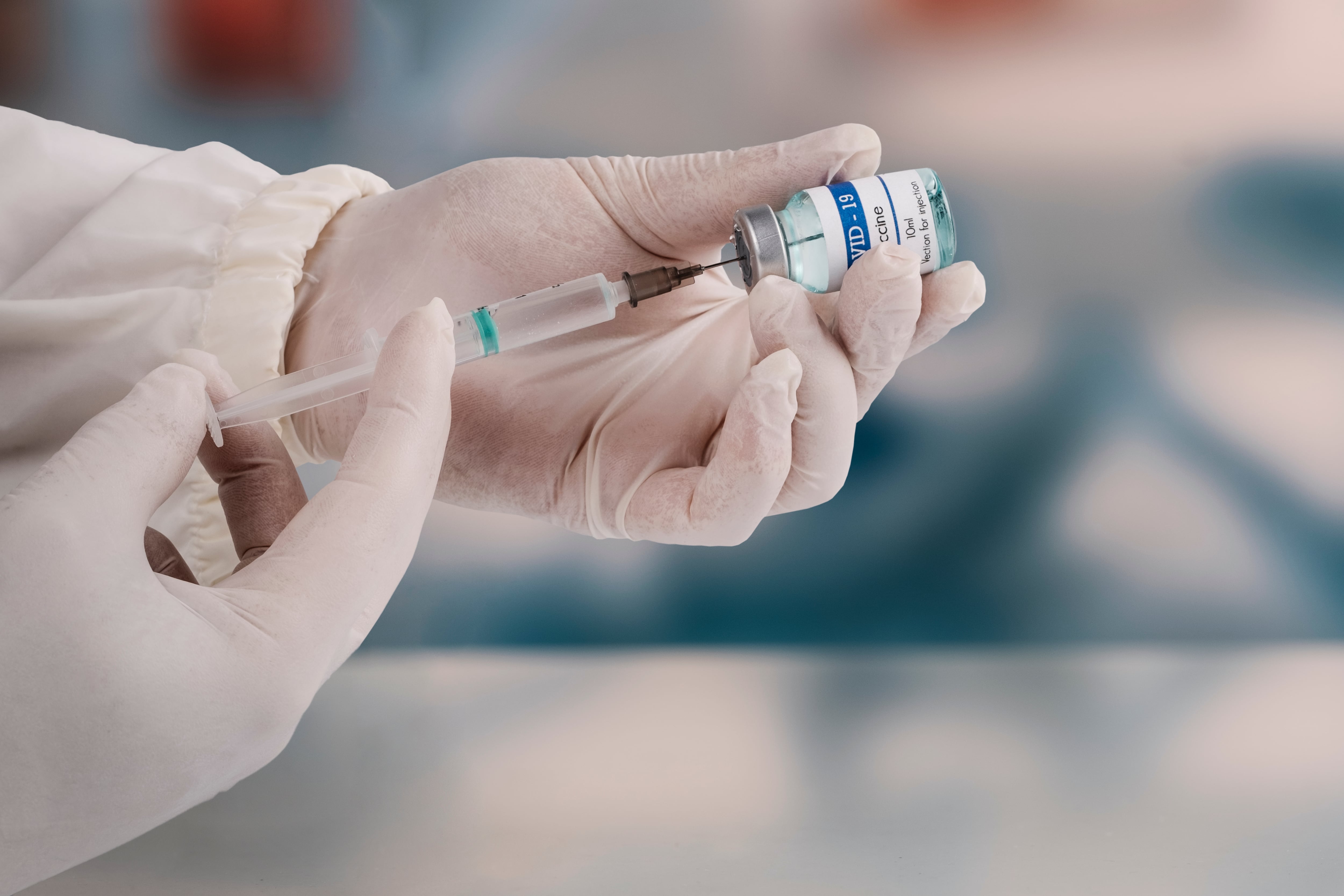 A doctor's gloved hands fill a syringe for a Covid-19 vaccination.