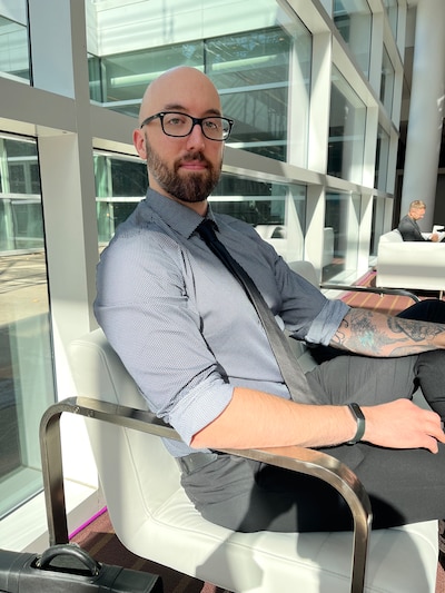A man sits in a chair near a window in an office.