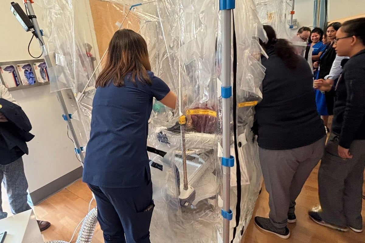 Hospital workers test a "care cube" containment system for treating a contagious patient.