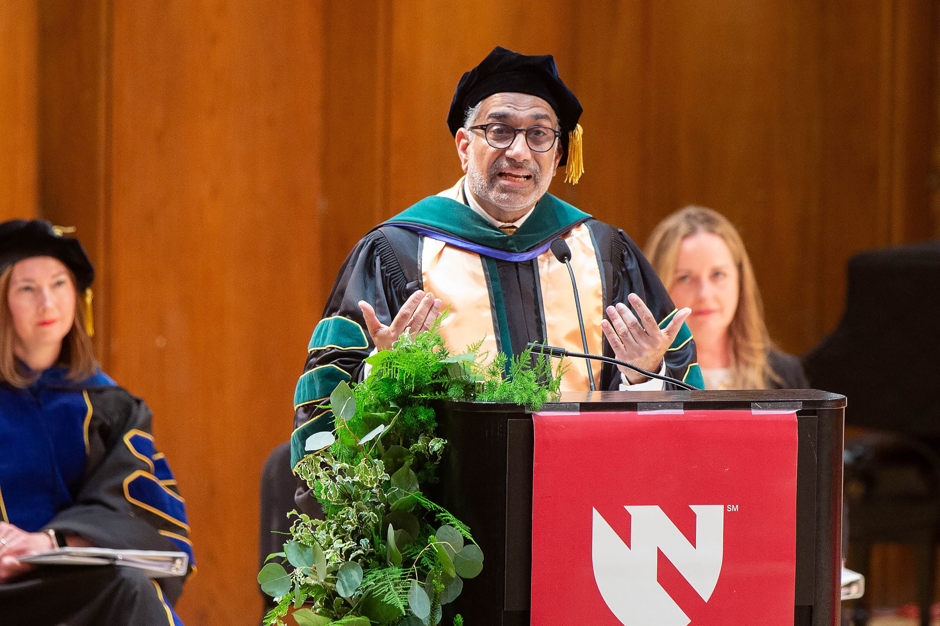 Dr. Ali Khan speaks from a podium at a commencement ceremony.