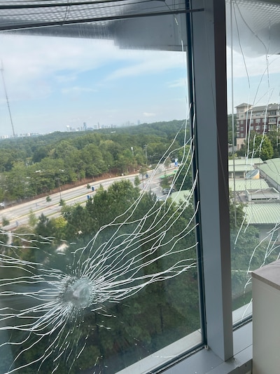 A window is cracked by bullet holes from a recent shooting.