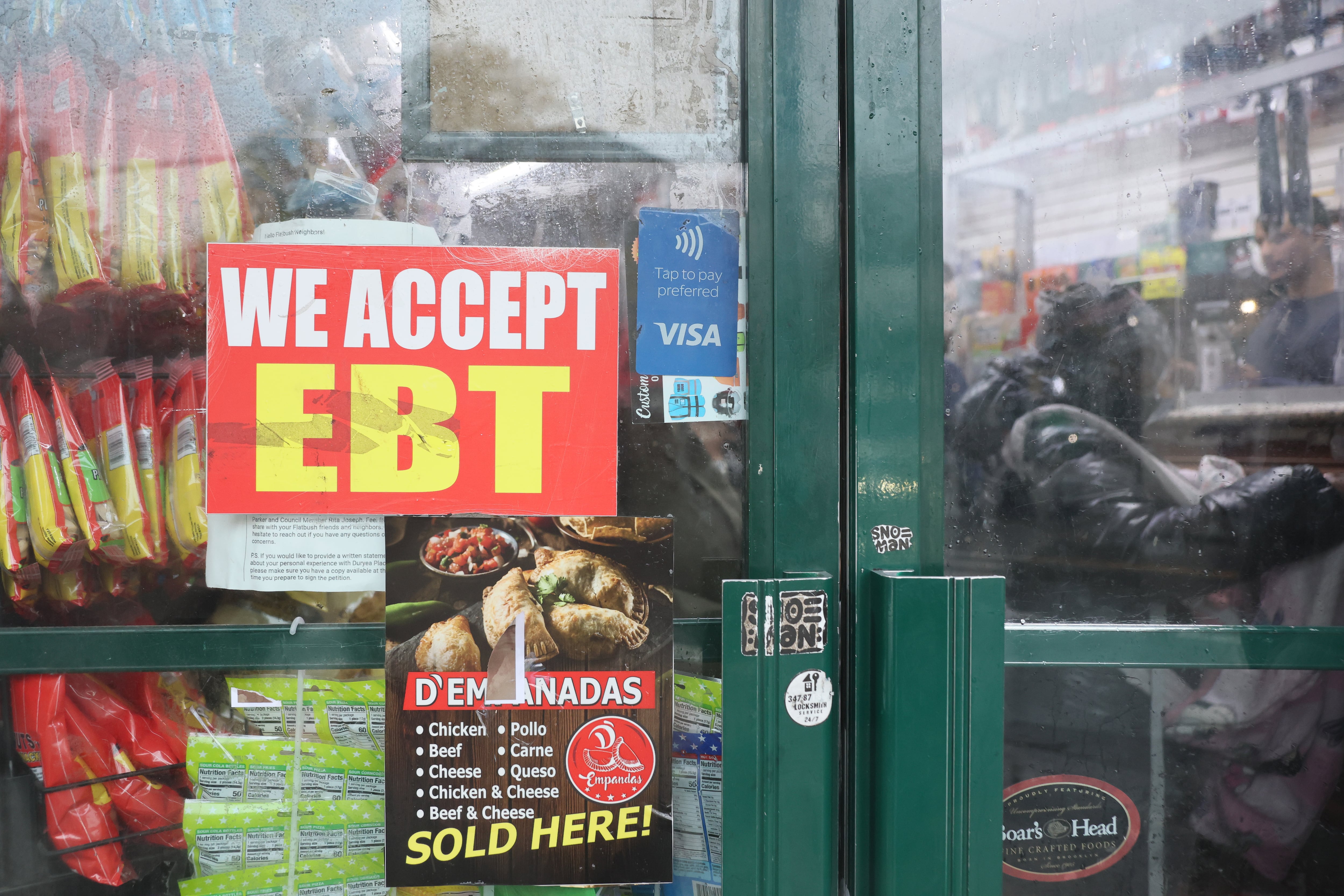A sign on a grocery store door says "We Accept EBT."