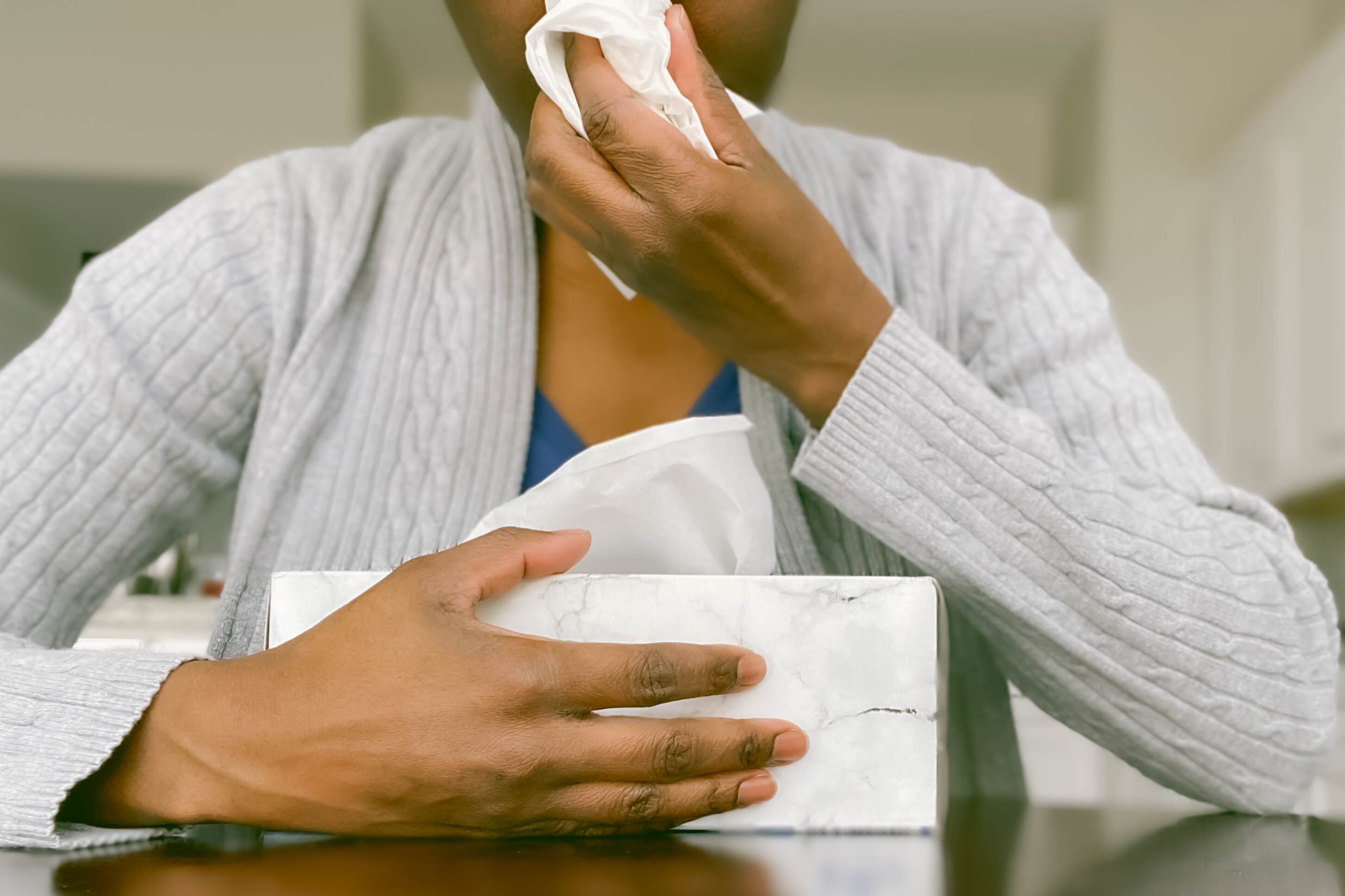 A woman holds a box of tissues.
