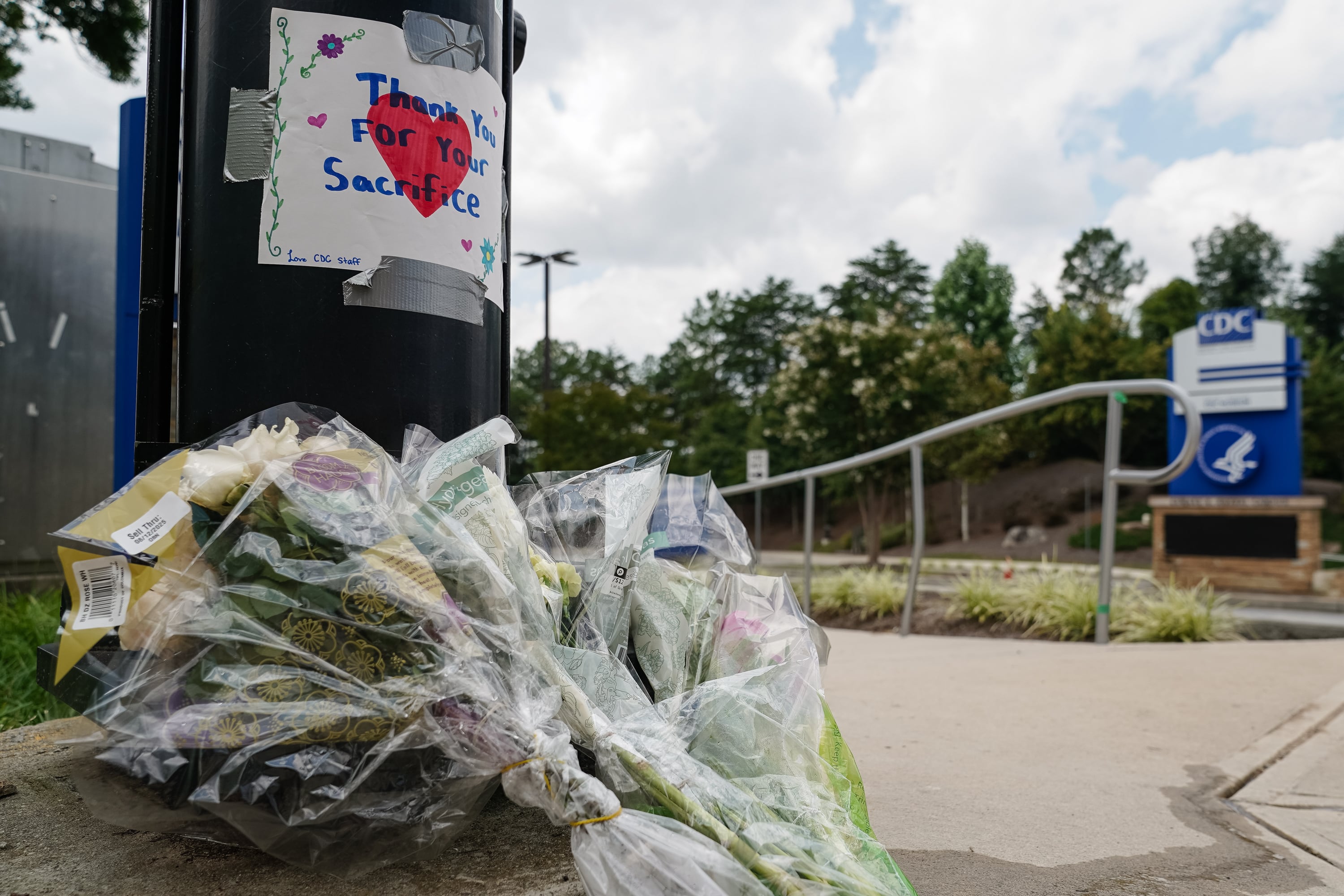 Flowers are laid beneath a handwritten sign outside CDC headquarters in Atlanta.