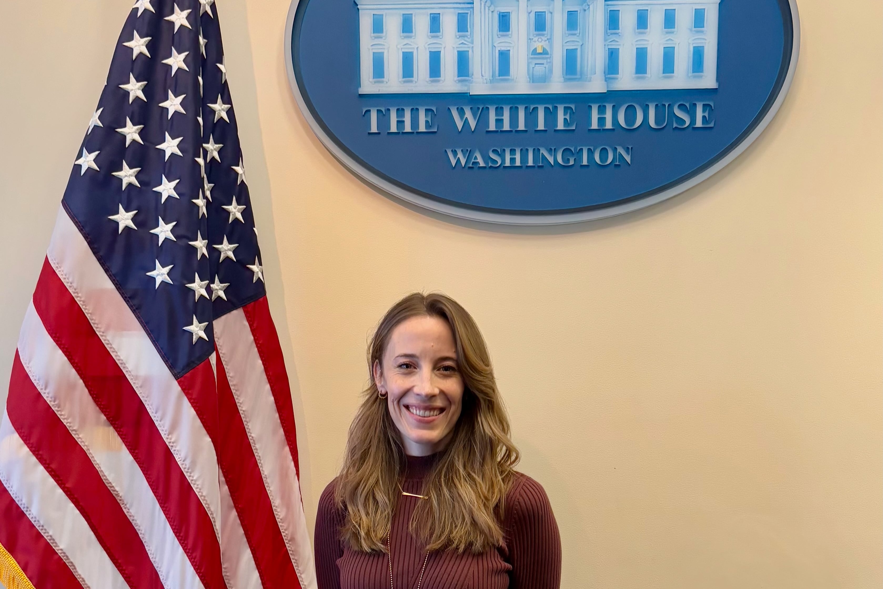 Marisa Donnelly poses in front of the White House seal and an American flag.