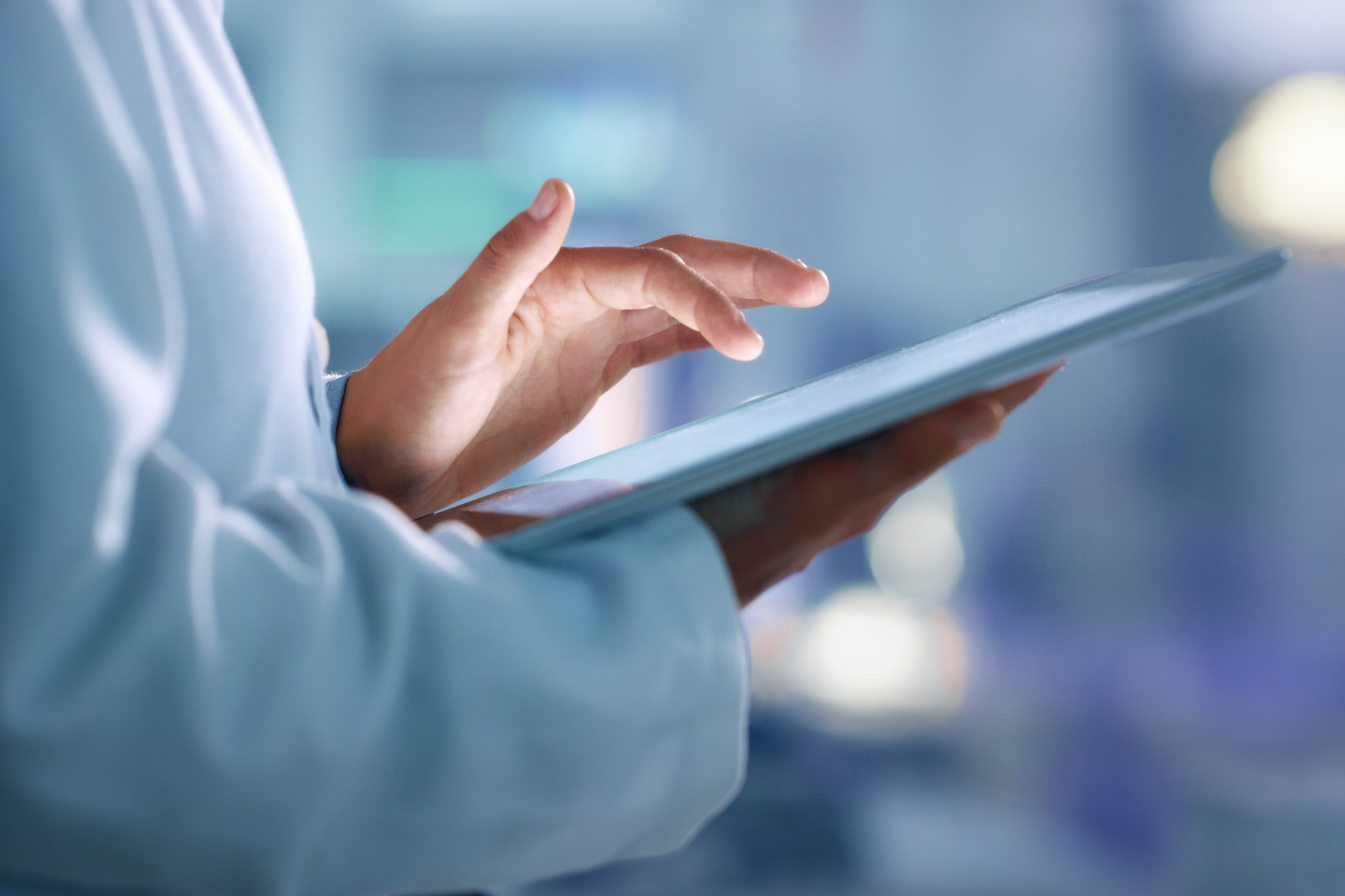 A person in a lab coat works from a tablet computer.